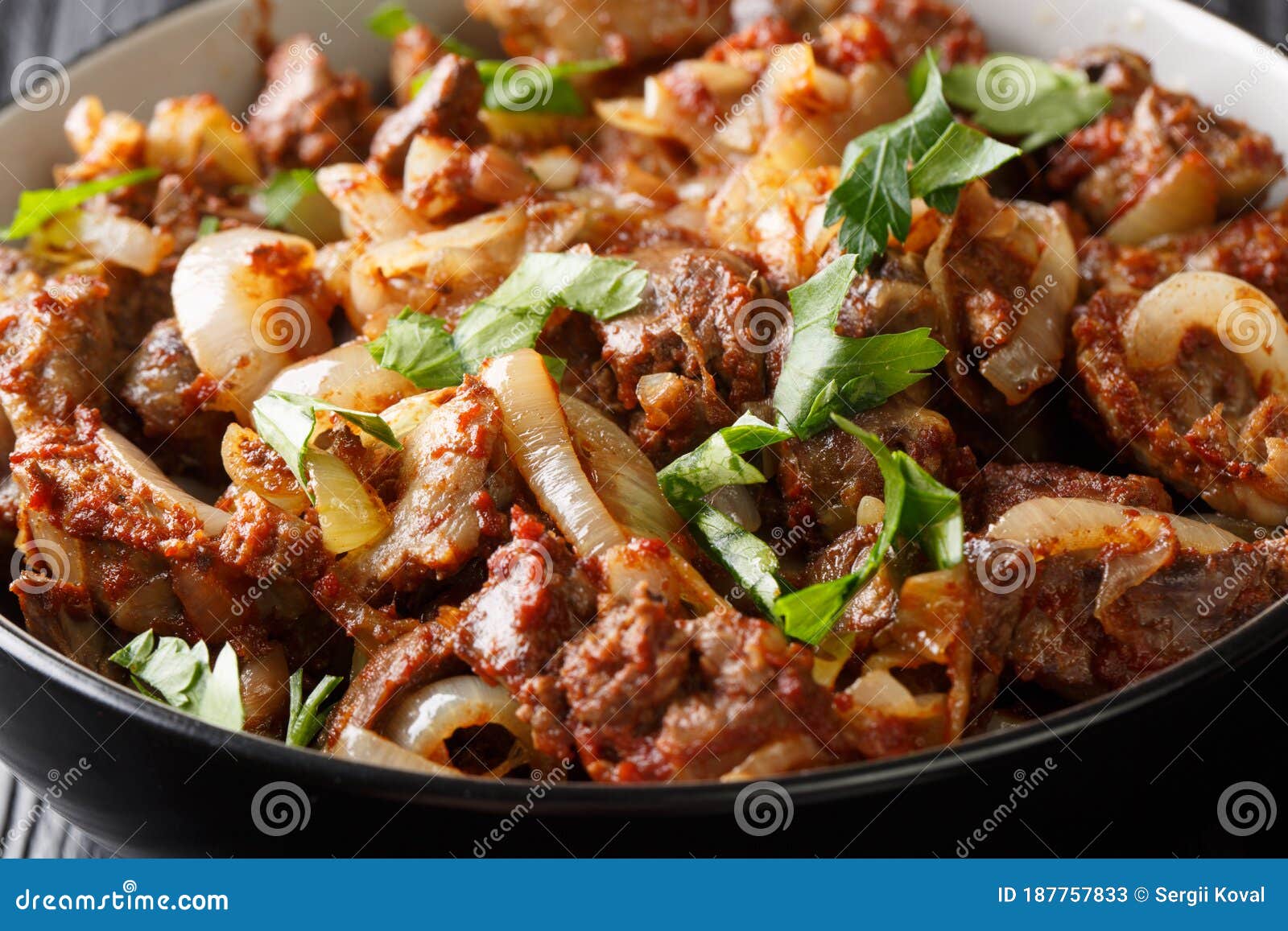 Fígado frito com cebola e especiarias num prato sobre a mesa