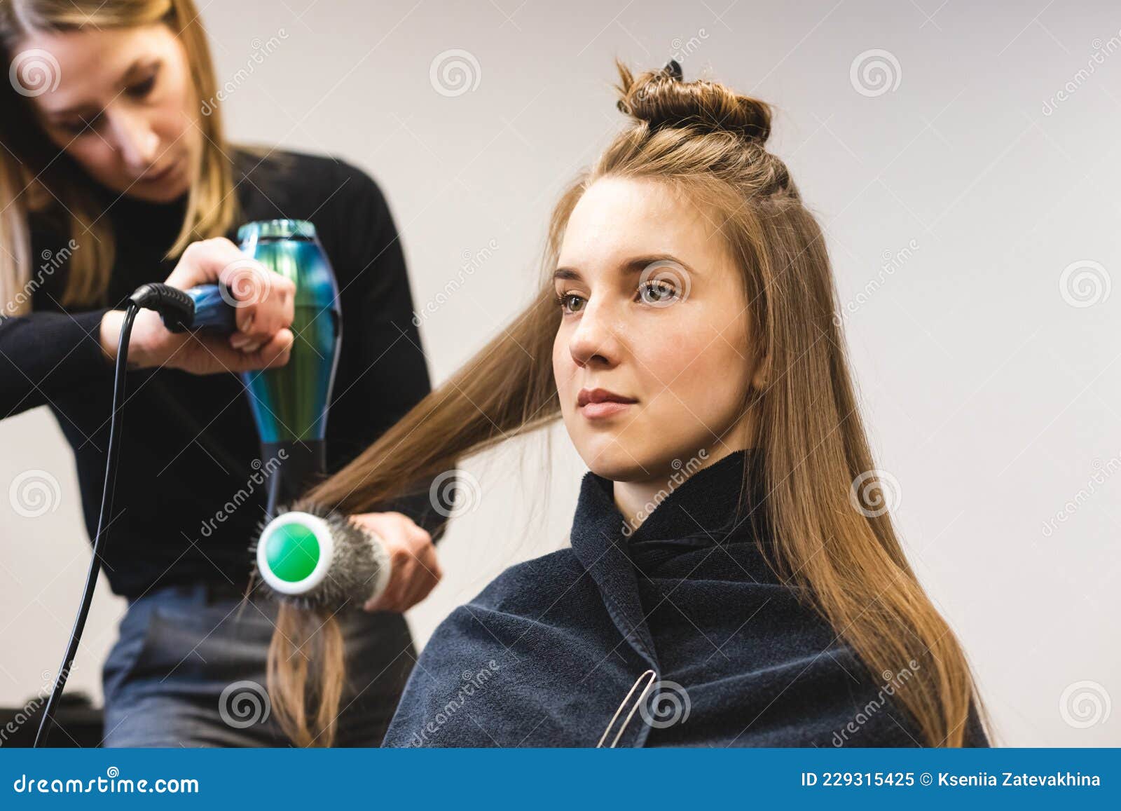 Cabeleireiro seca o cabelo com secador de cabelo para uma mulher