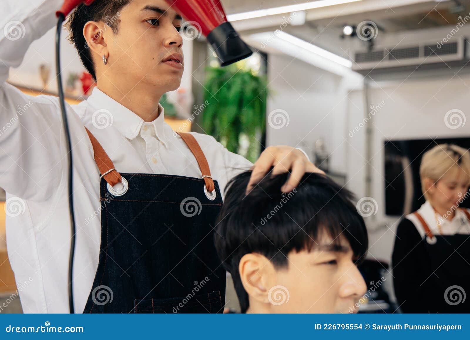 cabeleireiro secando o cabelo de seu cliente com um secador de