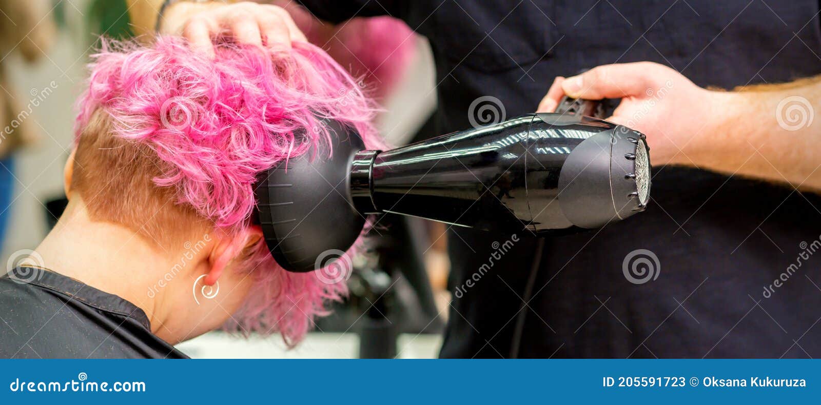 Cabeleireiro seca e modela o cabelo com um secador de cabelo no salão de  beleza