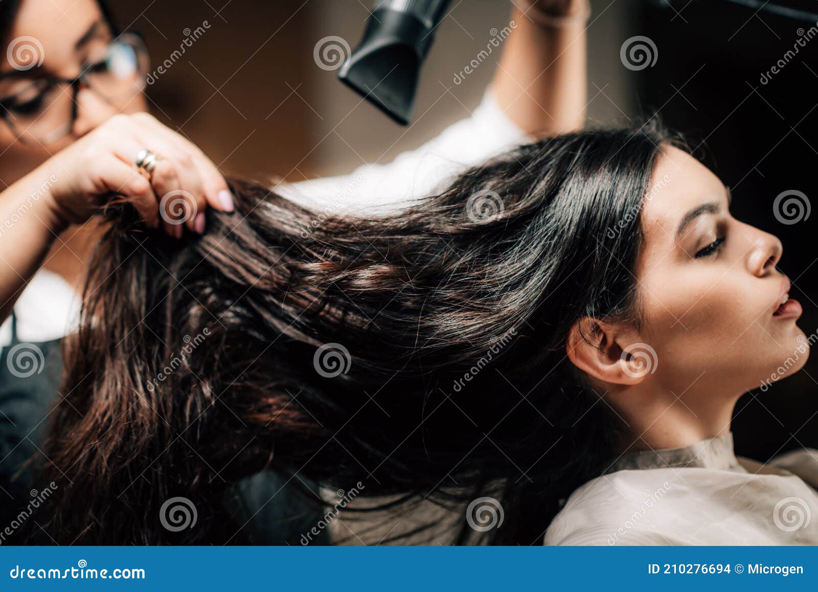 Cabeleireiro seca o cabelo com secador de cabelo para uma mulher após um  corte de cabelo no salão