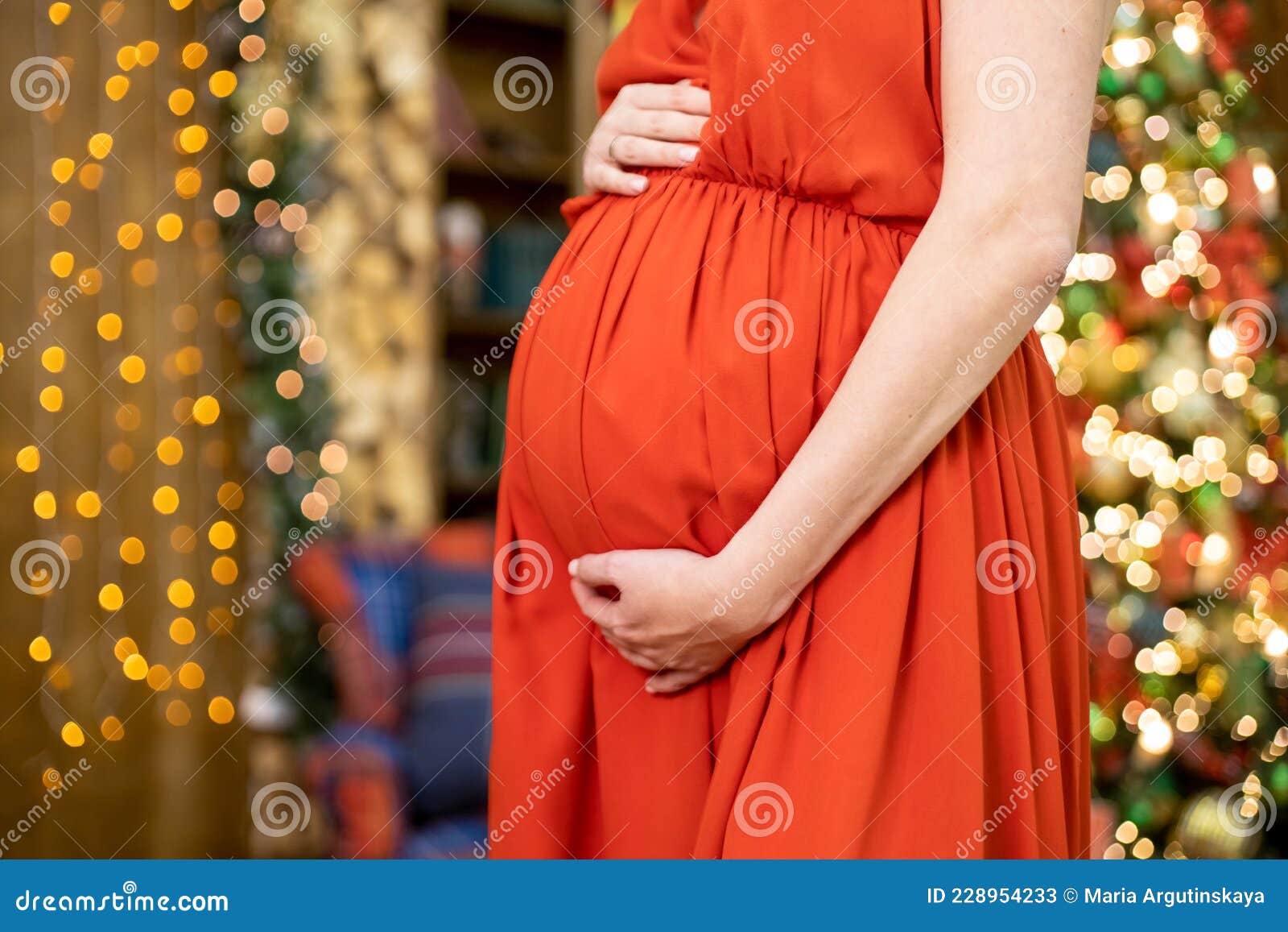 Cadeau De Noël. Femme Enceinte En Robe Rouge Serrant Son Ventre