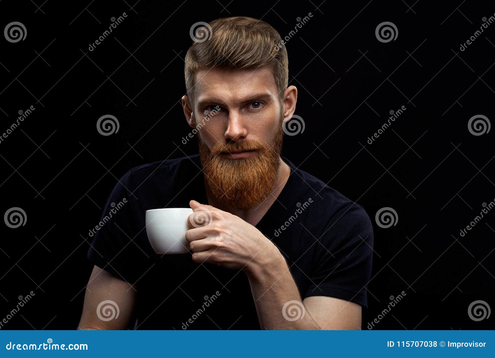 Caffè espresso bevente dell'uomo barbuto perfetto dell'acconciatura. Il caffè bevente del bello giovane uomo barbuto ed esaminare la macchina fotografica che riposa il caffè bevente del caffè espresso dell'uomo perfetto bello dell'acconciatura che tiene lo studio disponibile della tazza di caffè hanno sparato su fondo nero