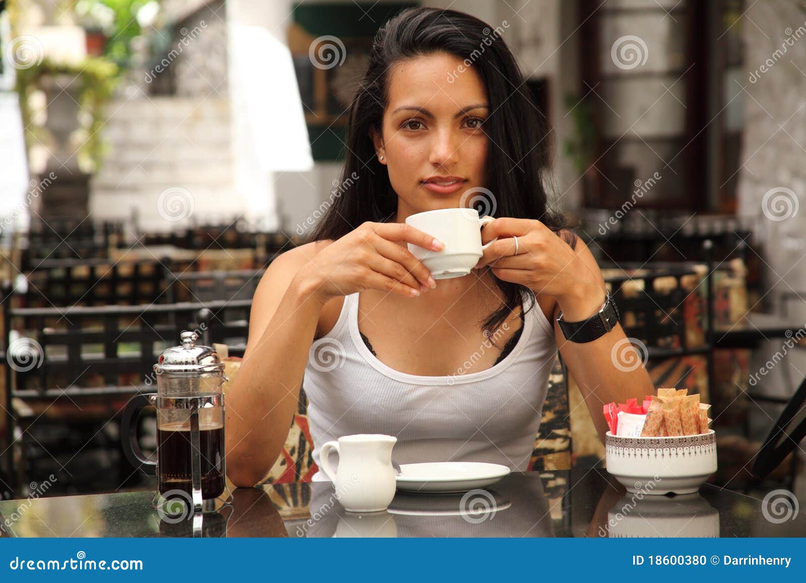 Café bebendo da mulher mediterrânea bonita. Mulher mediterrânea nova bonita que senta-se no café ao ar livre do pátio, café fresco bebendo