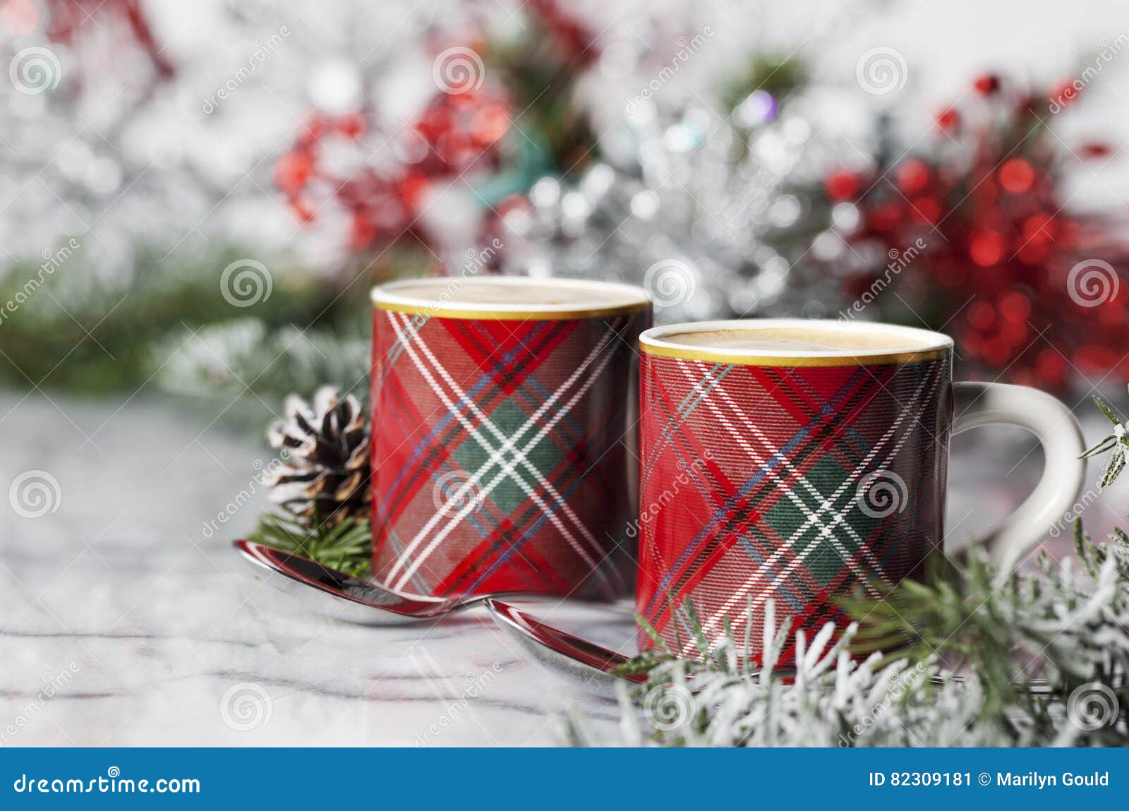 Café do Natal. Dois copos do demitasse da manta encheram-se com o café, os ramo sempre-verdes no primeiro plano com vermelho e o bokeh da prata no fundo