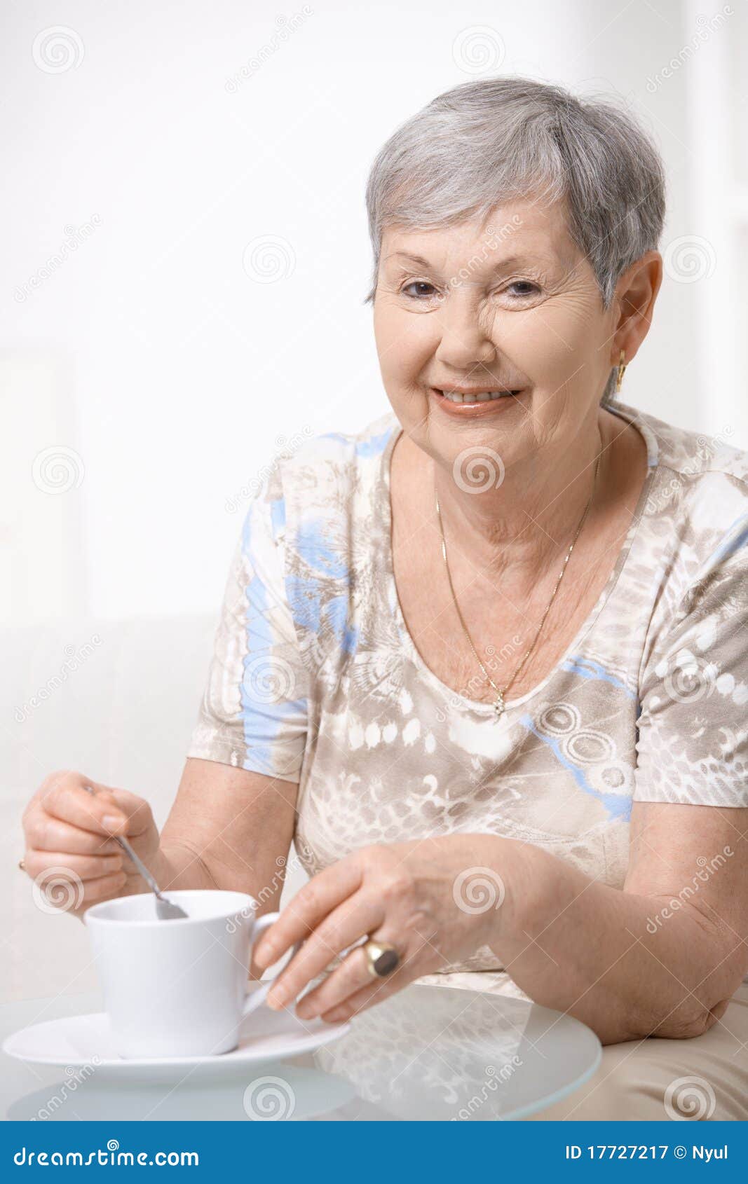 Café potable de femme aîné heureux. Femme aînée heureuse s'asseyant à la table, café potable, souriant.