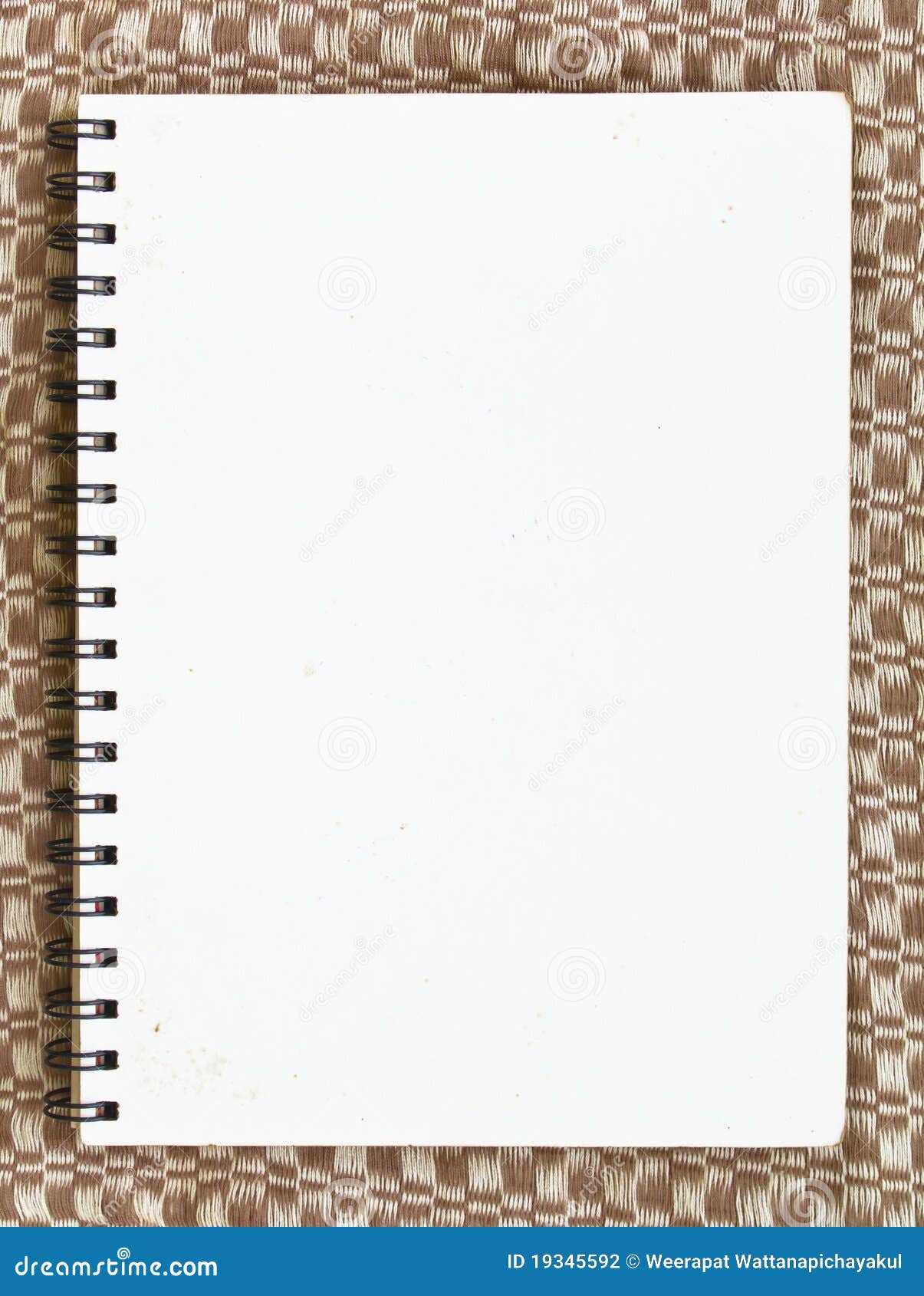 Cahier sur le tissu. Page blanc de carnet de notes à spirale sur le tissu brun