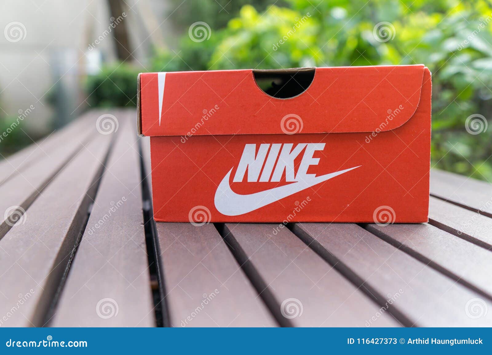 Caja Del Rojo De Nike , Zapatos Del Nike De La Caja En La Carretera De Asfalto En El Parque Con El Espacio De La Copia Para El Te Foto archivo