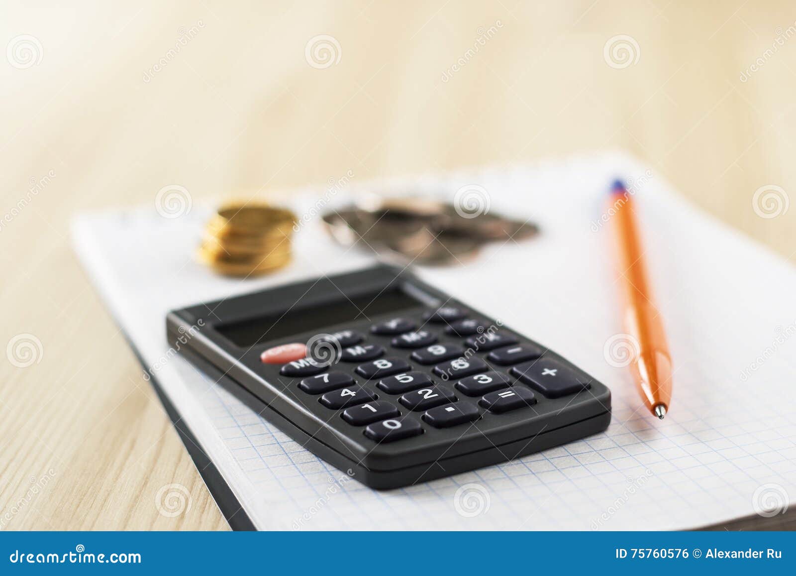 Calculator, pen, coins lie on notebook.
