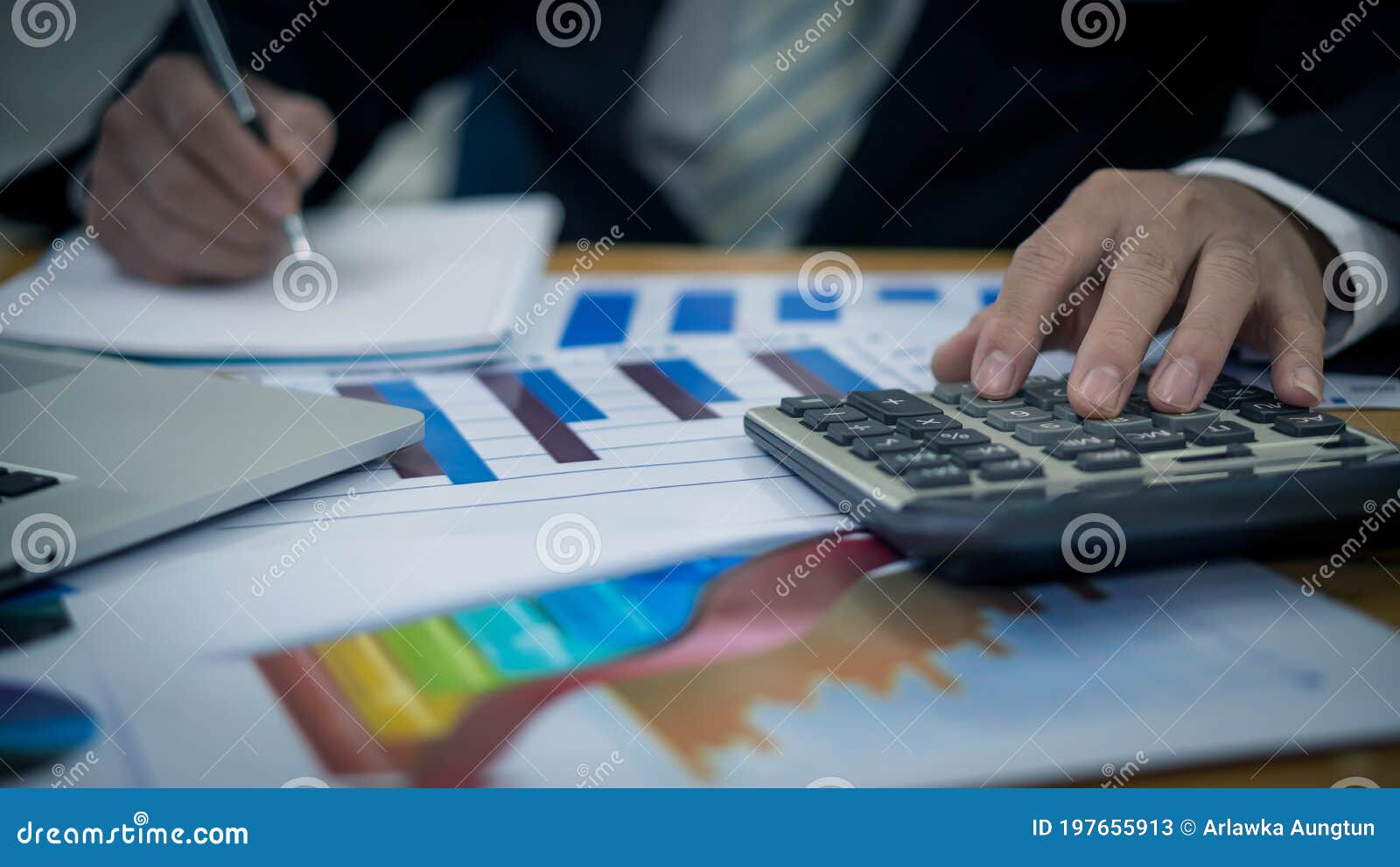 Calculators Placed on Graphs and Businessmen are Writing Their Designs