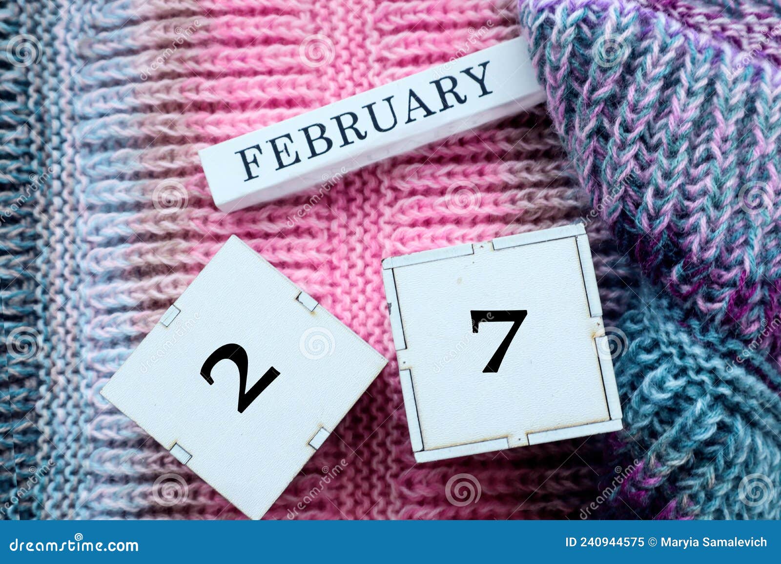 calendar for february 27: cubes with the numbers 27, the name of the month of february in english on multi-colored jersey, top