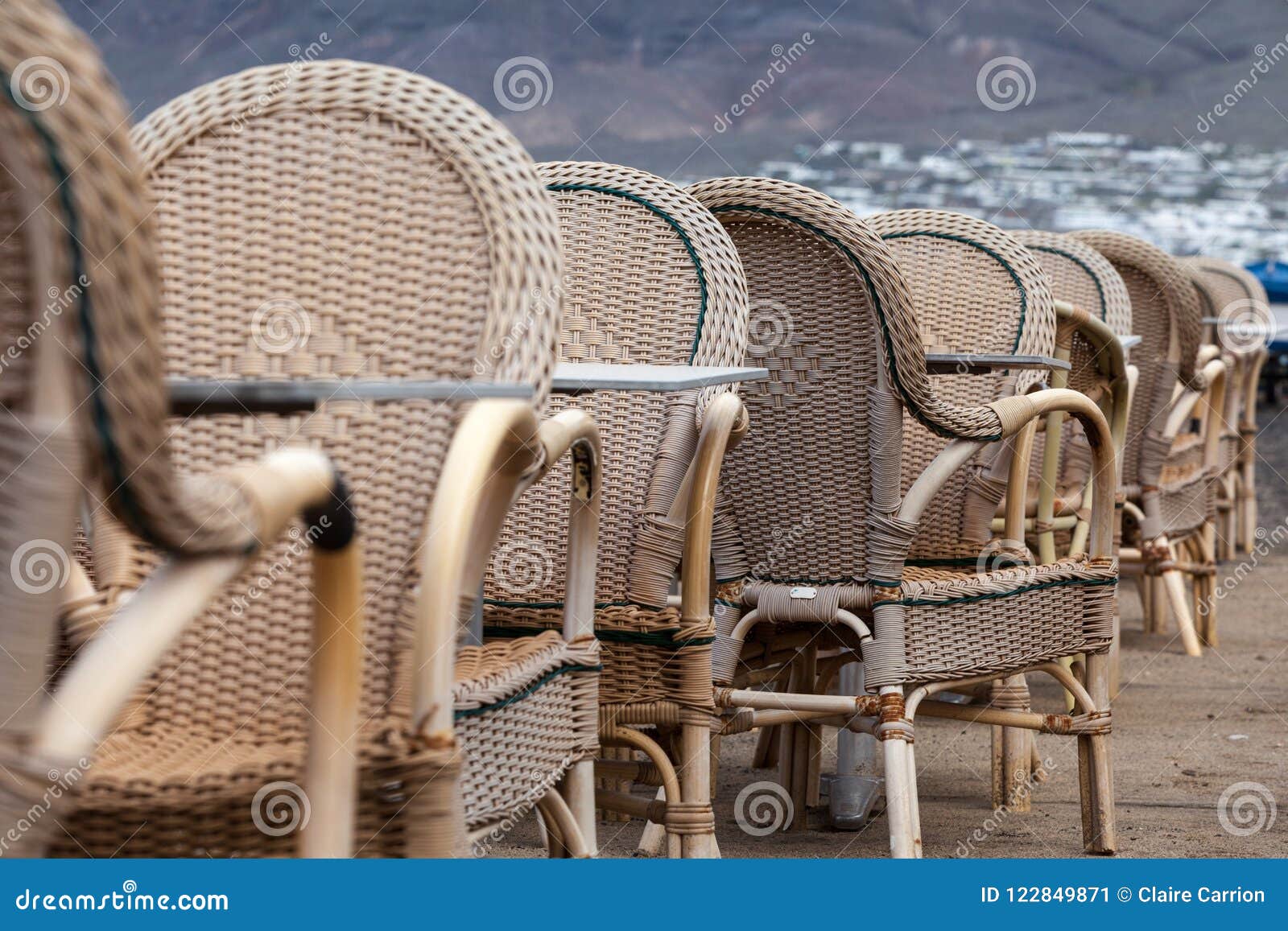 caleta de famara/spain - february 2, 2018: chairs and tables of an empty outdoor restaurant with the sea in the background