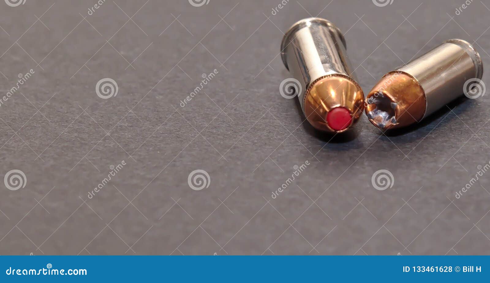 A 40 Caliber Hollow Point Bullet And A 44spl Red Tipped Bullet Laying Toget...