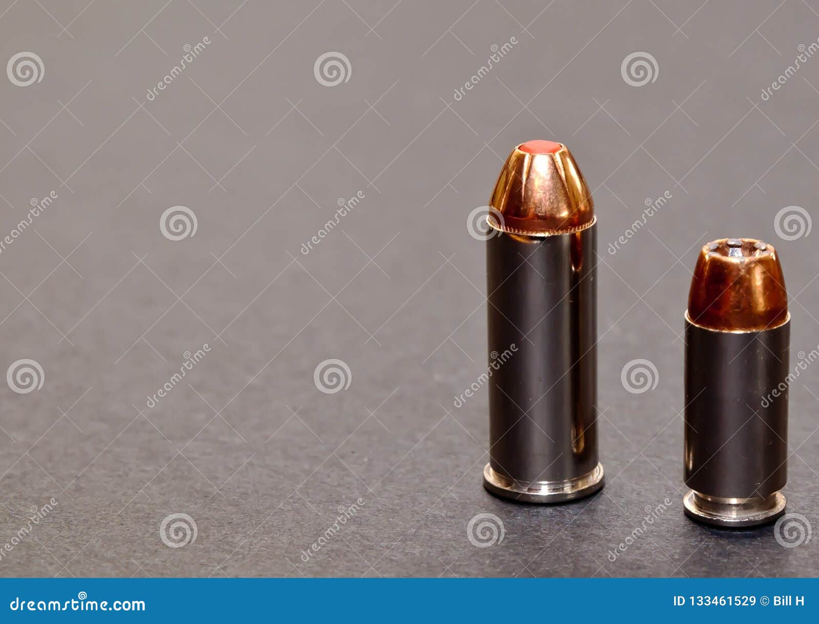 a 40 caliber hollow point bullet and a 44spl red tipped bullet together on a gray background