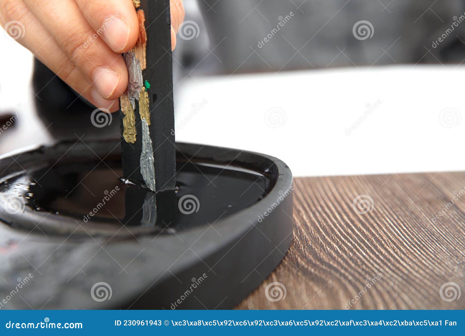 the calligrapher is studying ink on the inkstone with ink sticks in hand