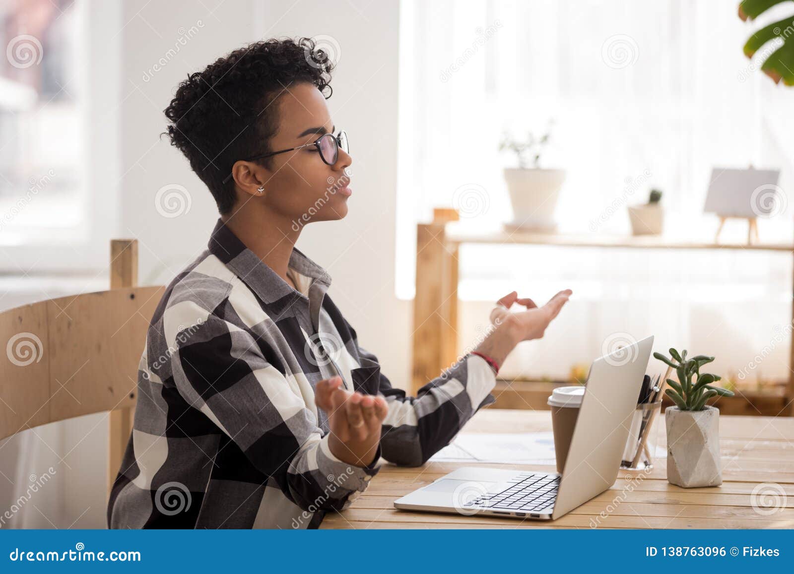 Calm African Woman Taking Break Doing Yoga At Office Desk Stock