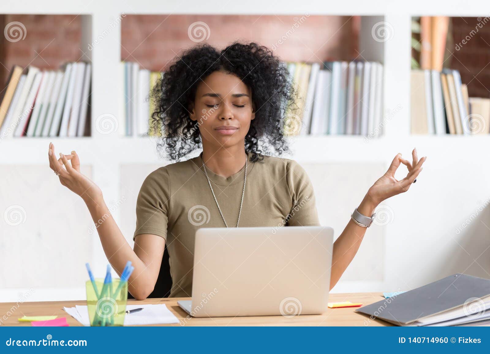 calm black businesswoman taking break meditating doing yoga at work