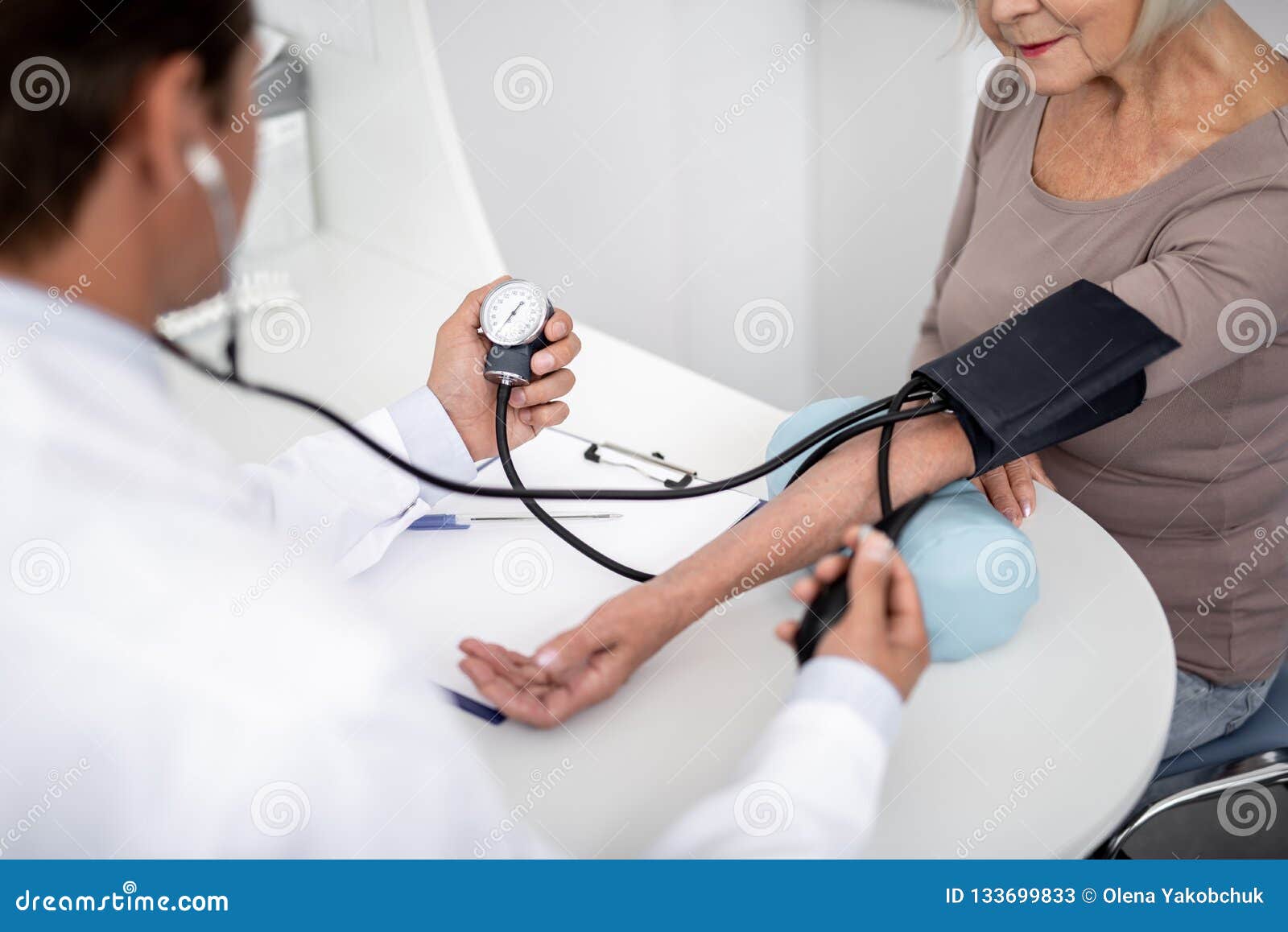 Female Doctor Measuring Blood Pressure Man In Hospital 