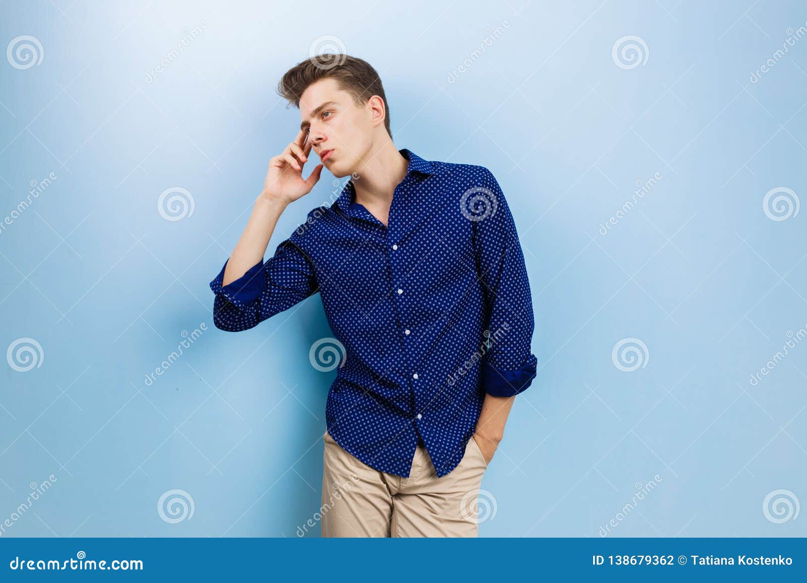 A calm relaxed man wearing a light blue shirt with beige pants, standing  against a white background. Carefree and relaxed looking at camera. Stock  Photo | Adobe Stock