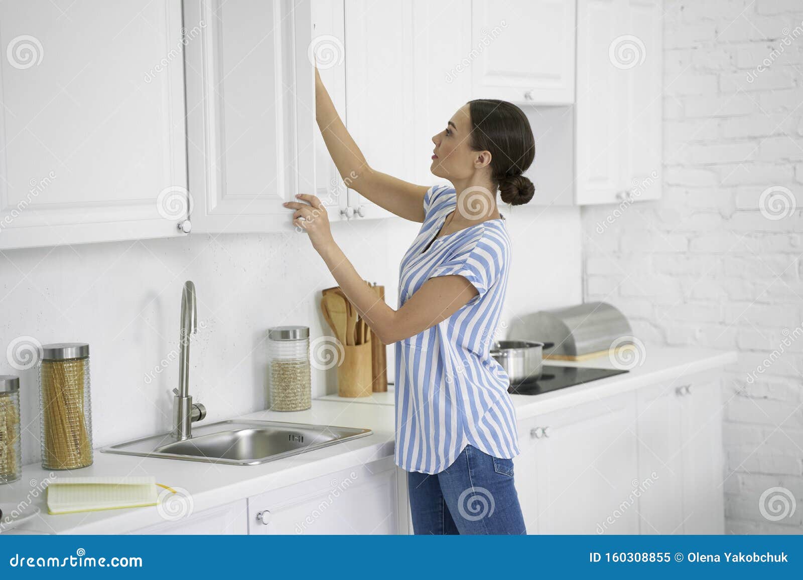 woman opening the kitchen cupboard stock photo