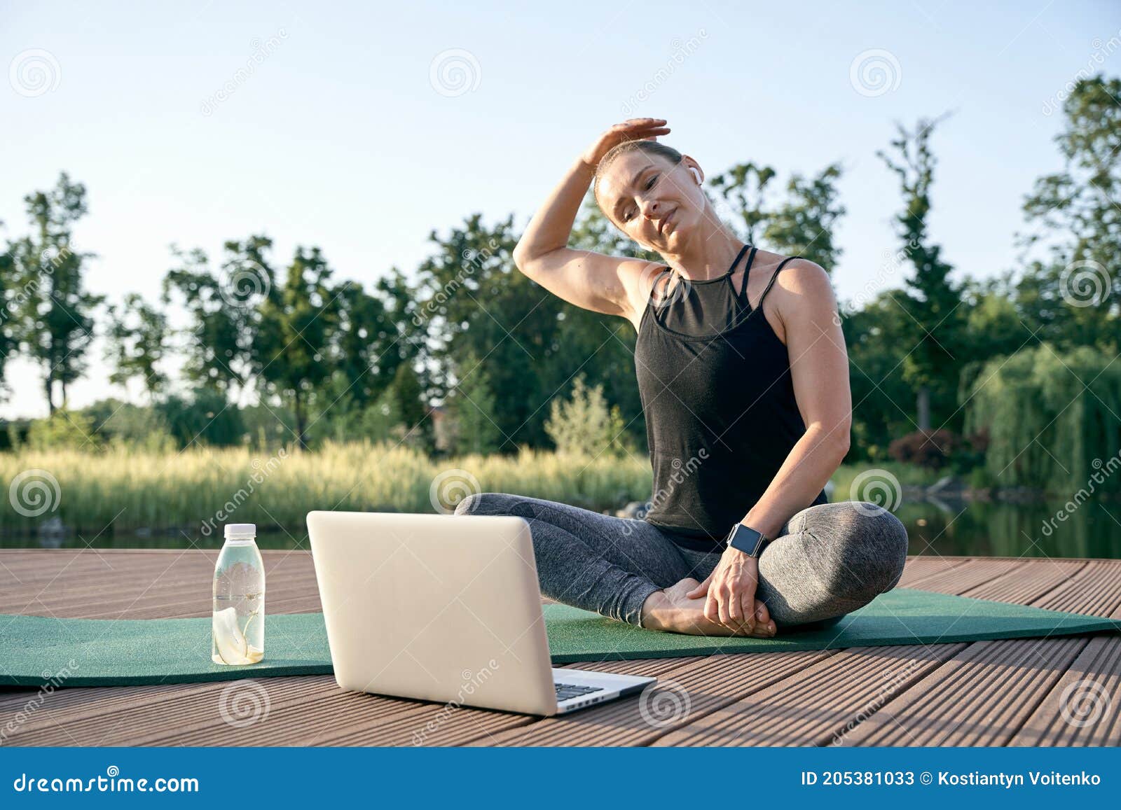 calm your mind. athletic beautiful middle aged woman watching instructional videos on a laptop while exercising on a mat