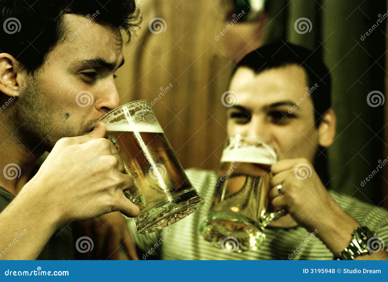 Camaradas que comem uma cerveja junto. Dois homens tomam um sip de suas canecas de cerveja, apreciando a companhia de cada um em um restaurante. A imagem mostra o ruído.