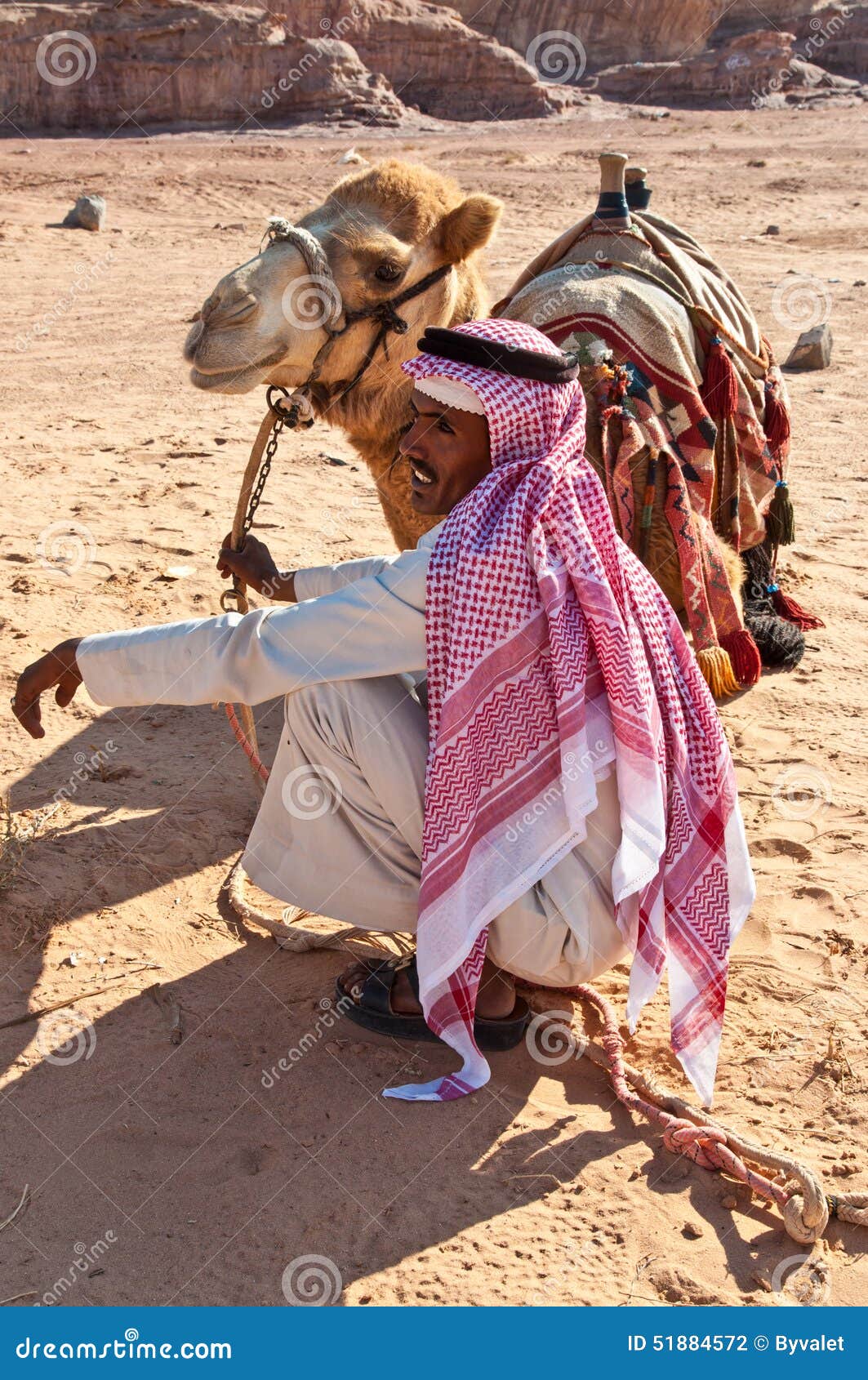 Camelo e beduíno no deserto. Wadi Rum, Jordânia - 20 de novembro de 2010: Turistas de espera do beduíno do camelo e do árabe na paisagem do deserto no 20 de novembro de 2010 no vale de Wadi Rum, Jordânia