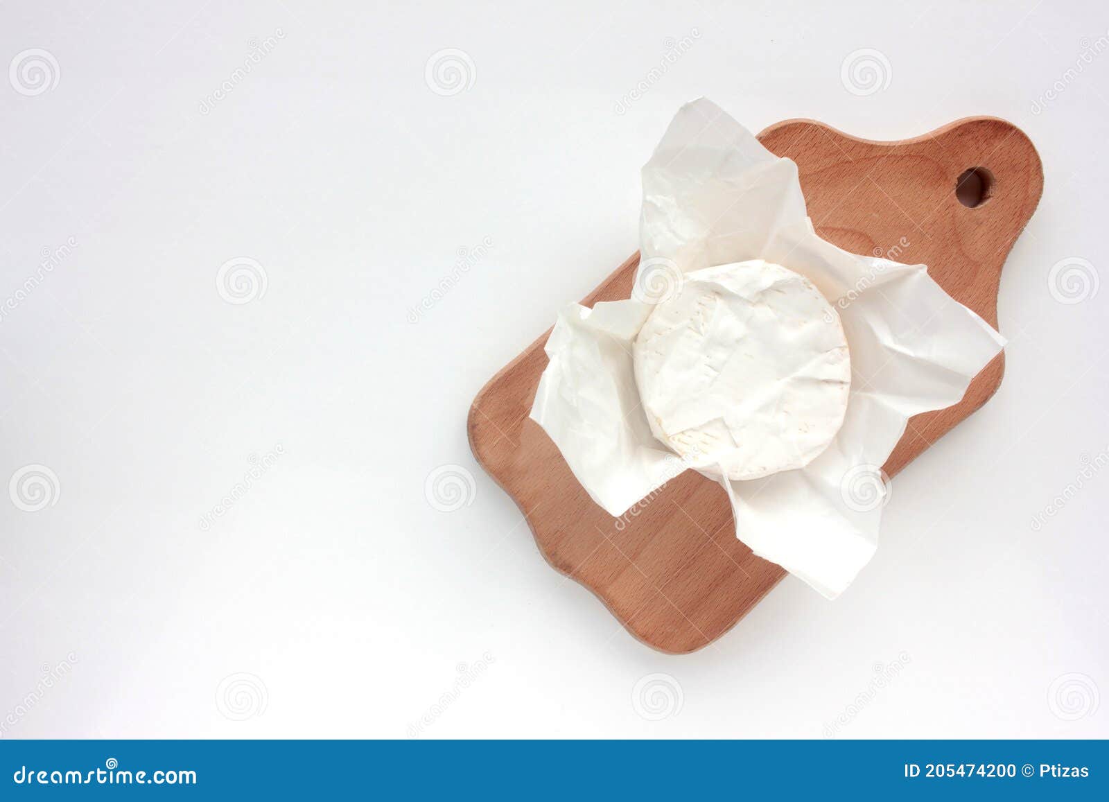camembert cheese on white packaging paper. top view. close up of white cheese on cutting board on white table
