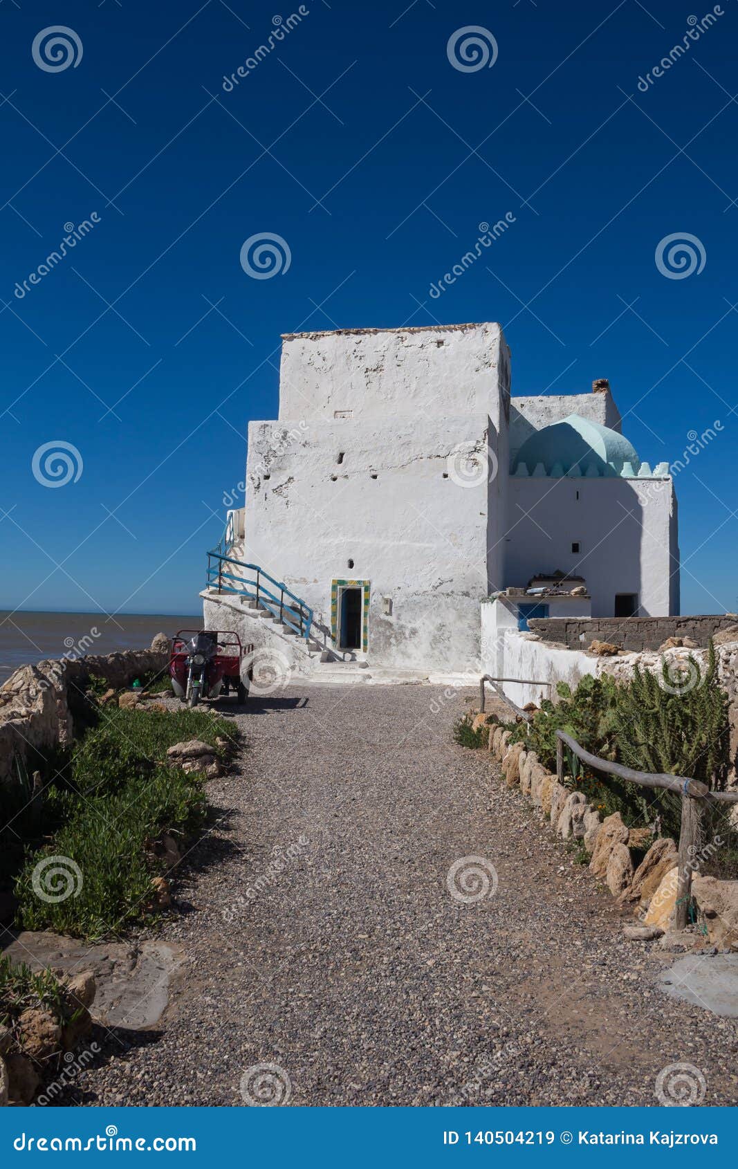Camera alla costa, Sidi Kaouki, Marocco. Vecchia casa sulla costa delle rocce dell'Oceano Atlantico Pareti bianche sopravvissute a causa dell'acqua, della sabbia e del vento Orizzonte dell'acqua Cielo blu luminoso Sidi Kaouki, Marocco