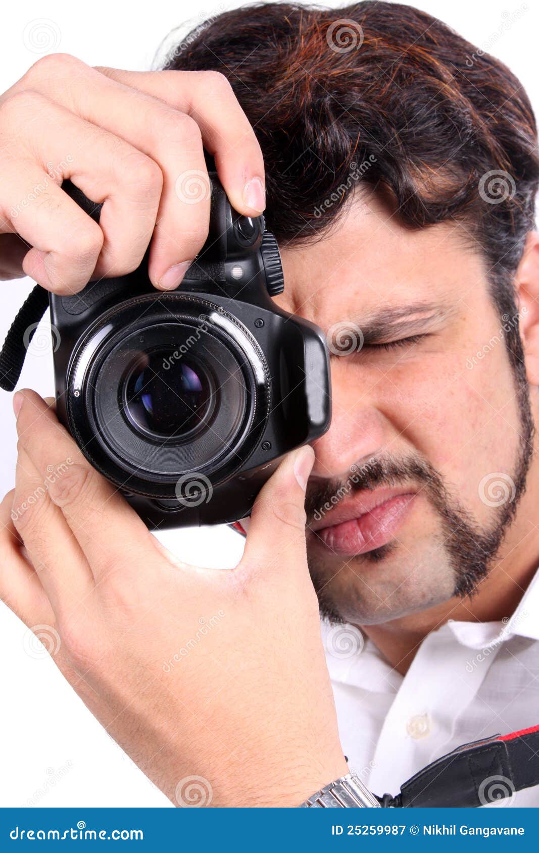 Camera Focus. A young Indian photographer closing his eye to focus his camera accurately.