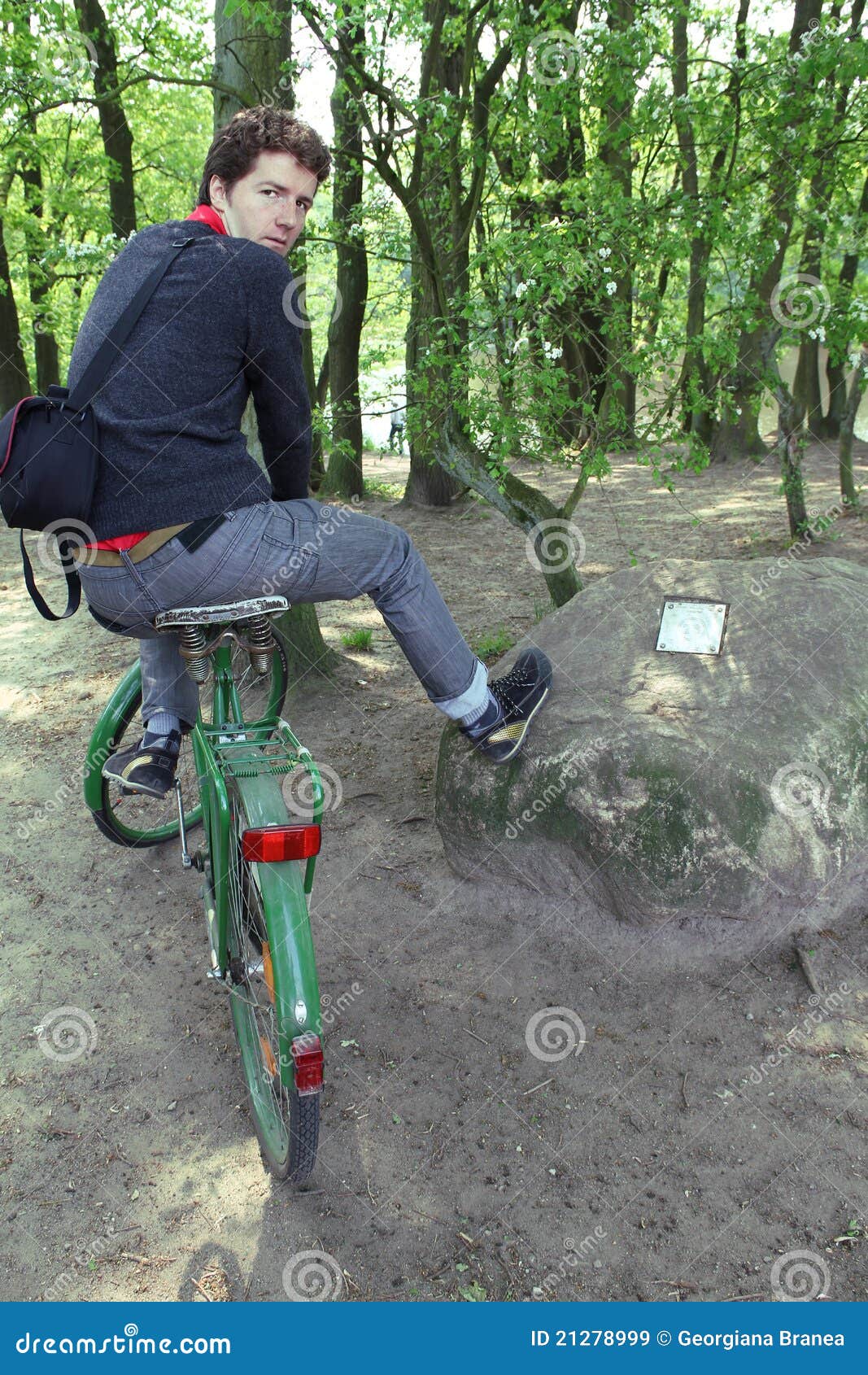 Caminata de la bici del bosque. Hombre joven en una bicicleta que toma un viaje en el bosque, caminando un jalón