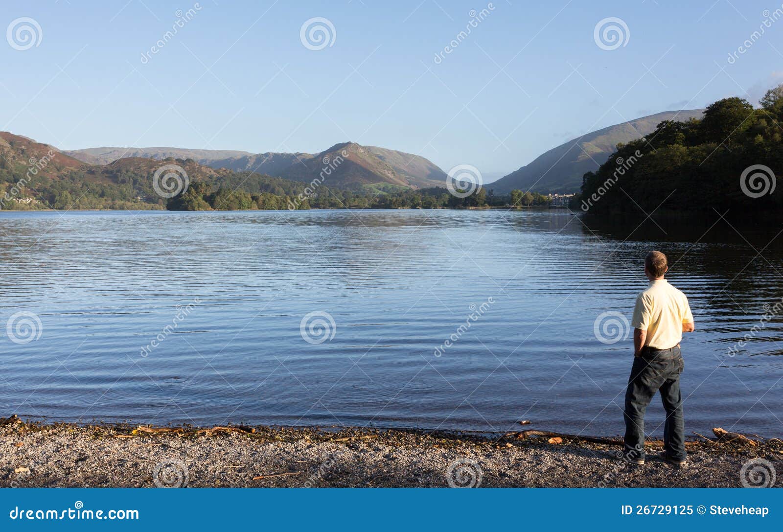 Caminhante em Grasmere no alvorecer no distrito do lago. O homem sênior negligencia Grasmere no distrito do lago como o nascer do sol como montanhas da luz do sol