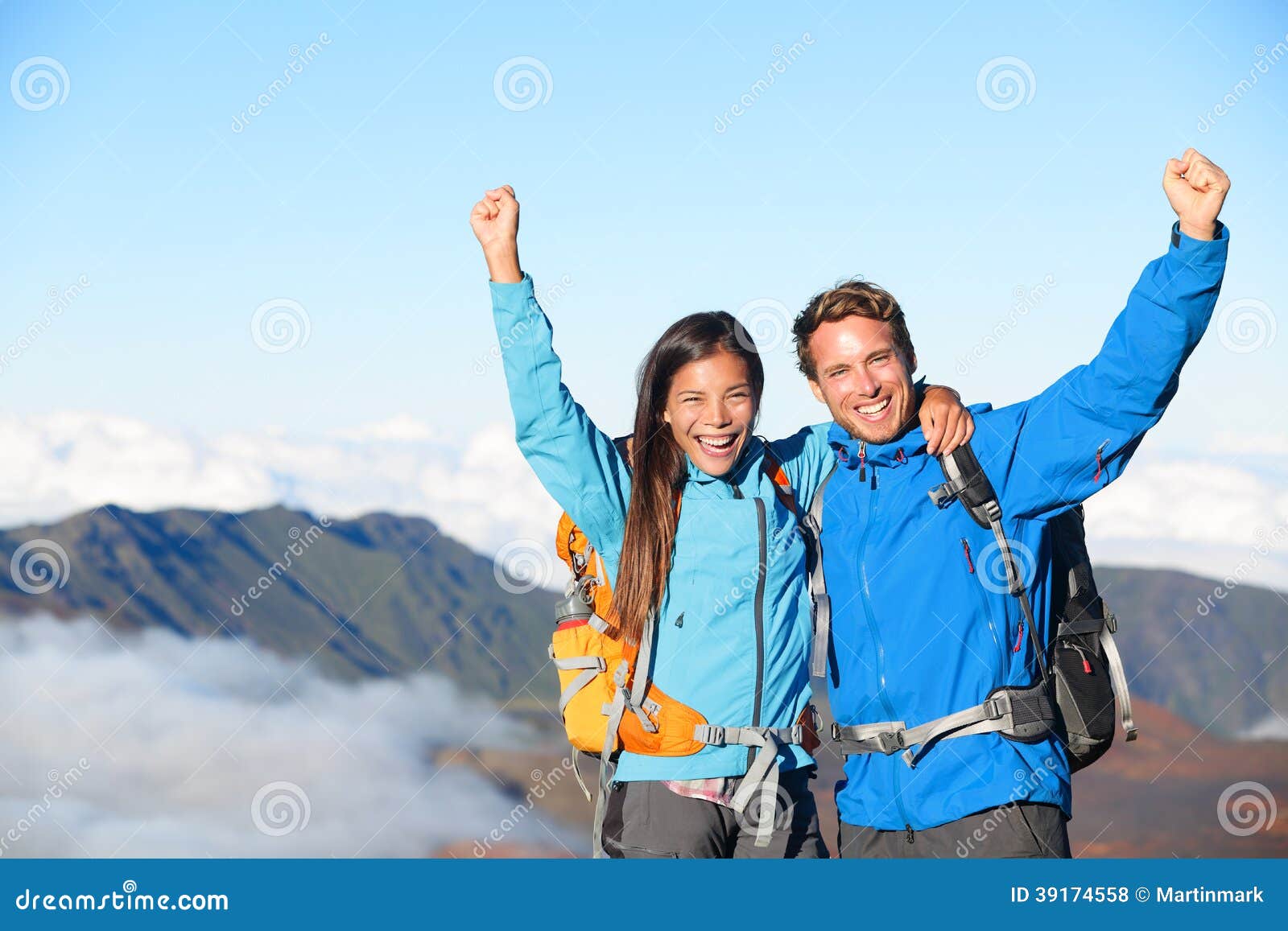 Caminhantes - povos que caminham cheering na parte superior da cimeira com vista no vulcão. Pares do caminhante que olham a paisagem bonita de vulcões da montanha, parque nacional Havaí de Haleakala, EUA. Povos retirados e felizes.