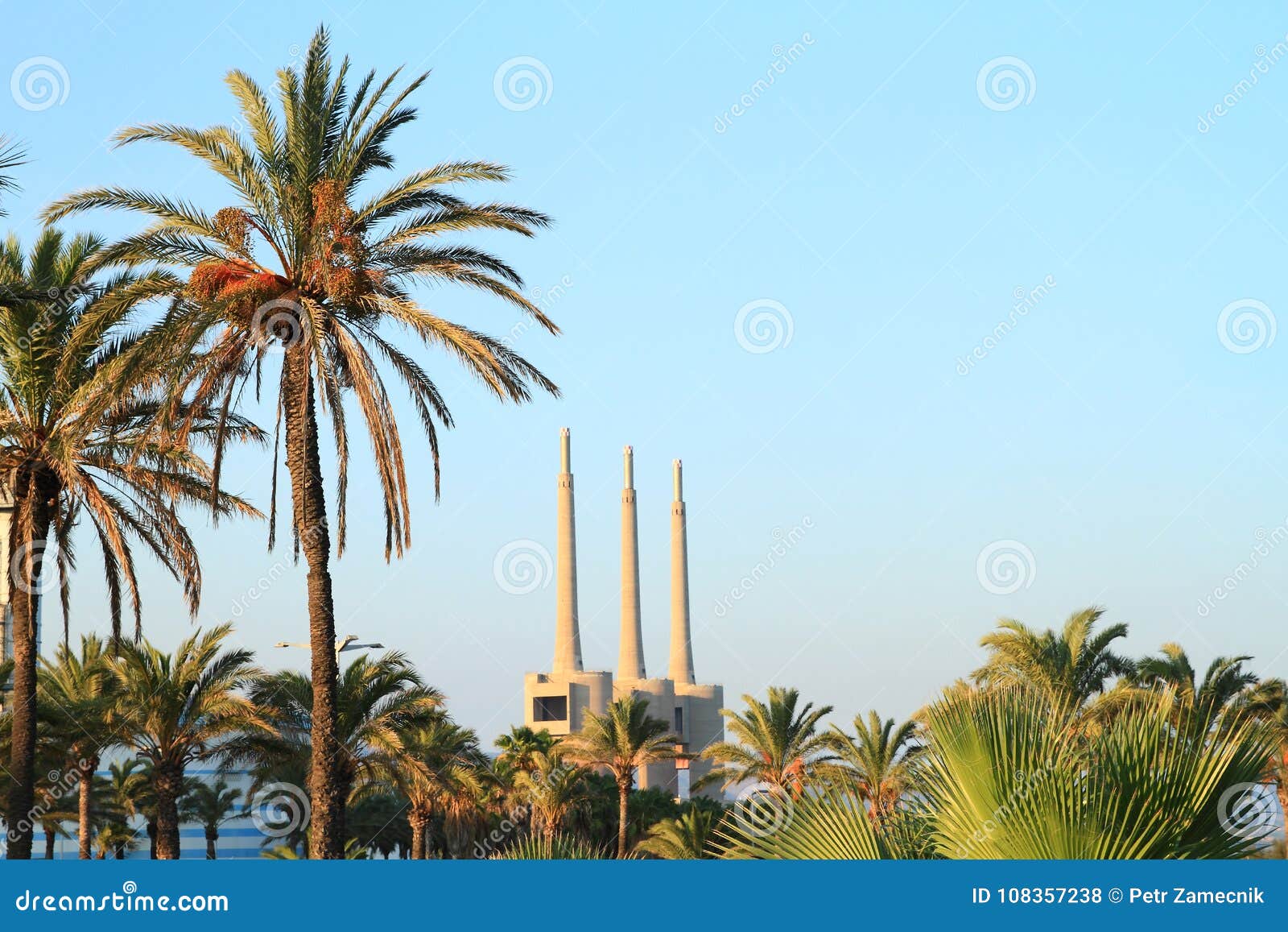 Camini della centrale elettrica del ciclo combinato del ² s di BesÃ dietro i palmtrees. Camini della centrale elettrica del ciclo combinato del ² s di BesÃ - installazione termoelettrica del ciclo combinato alimentata da gas naturale dietro i palmtrees, ² s, Barcellona, Spagna del ¡ n del BesÃ di San AdriÃ