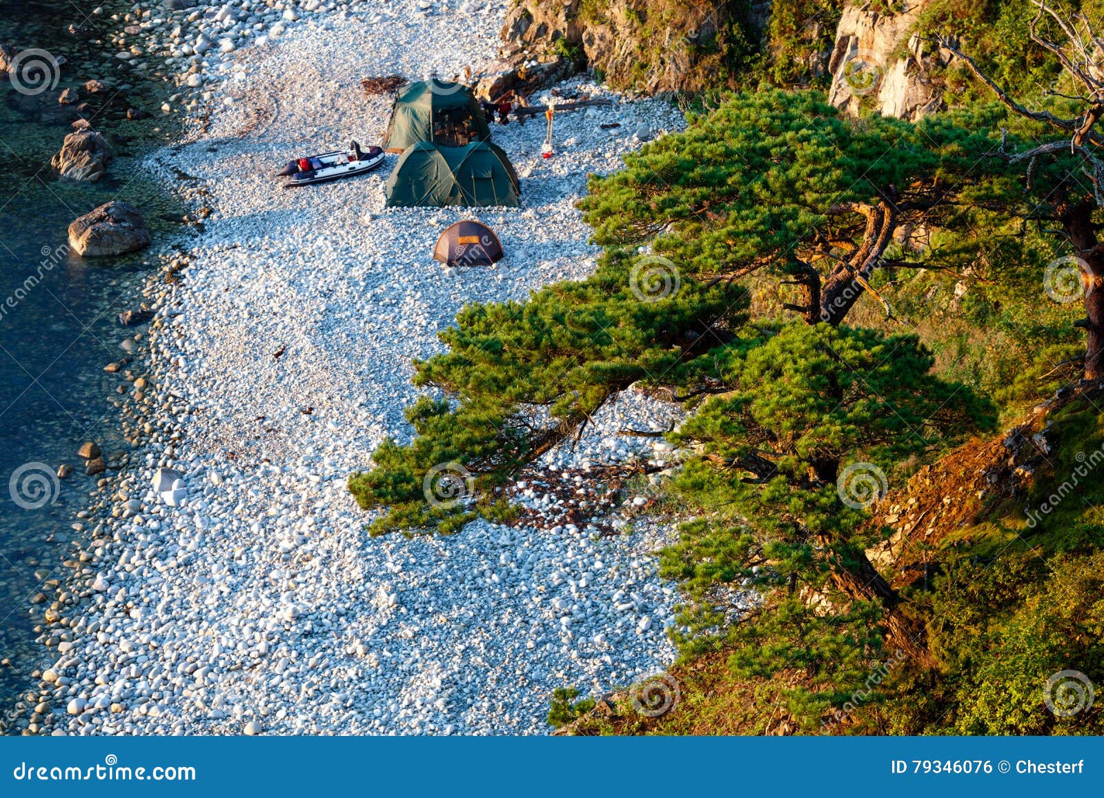 Camping with many tents on the beach at the seaside, view from hill, focus on the pine