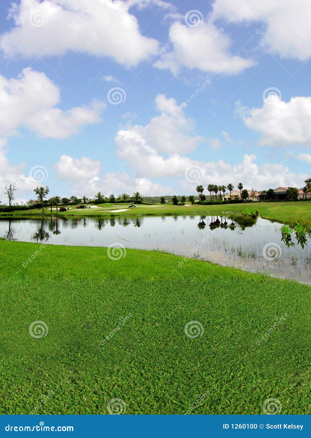 Campo de golf con opiniones del lago. Una opinión del lago adentro de una comunidad golfing, con los trabajadores en los verdes.