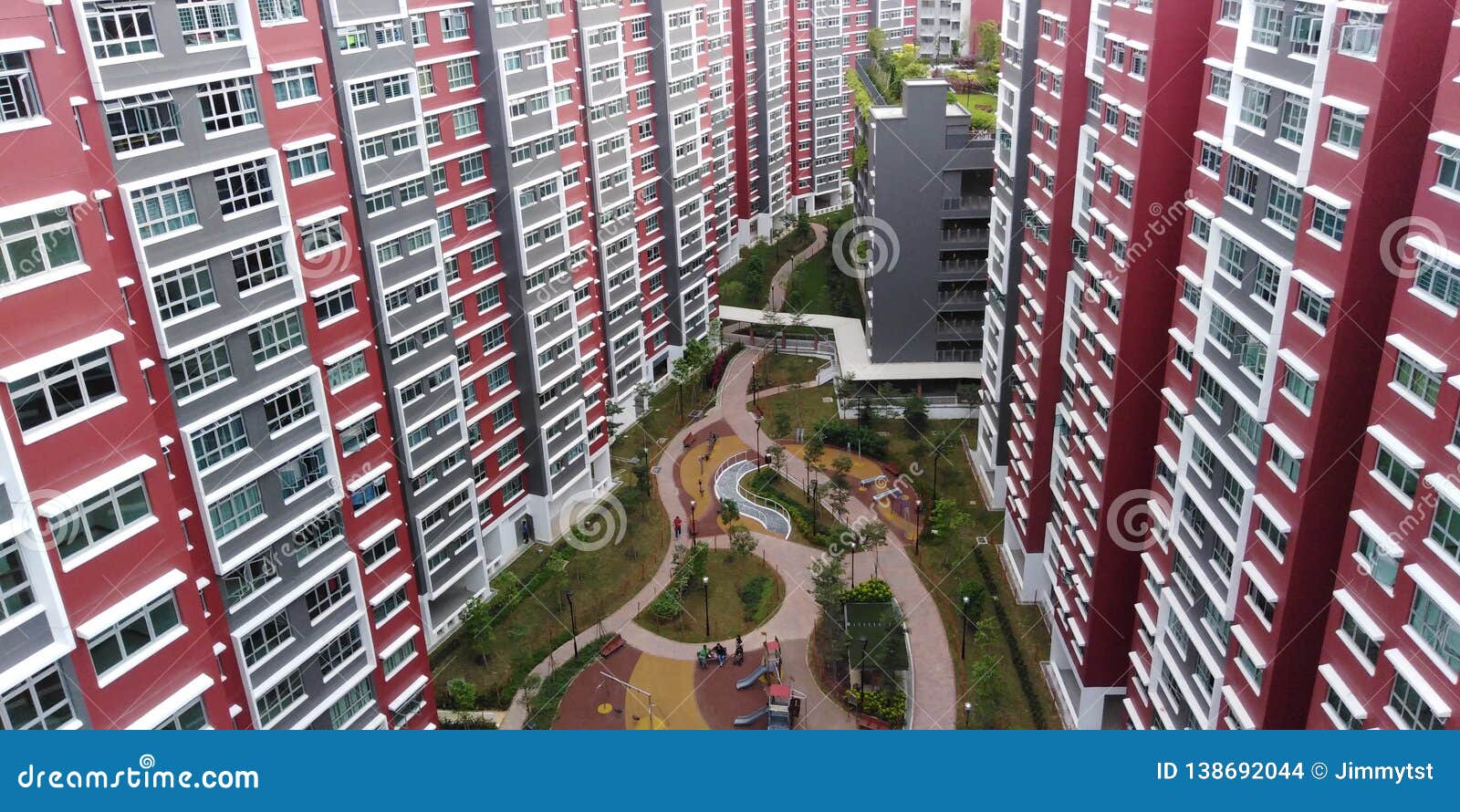 Campo de jogos na cidade moderna. Blocos residenciais novos de HDB com campo de jogos e o parque de estacionamento multistorey em Bukit Batok para o oeste, Singapura