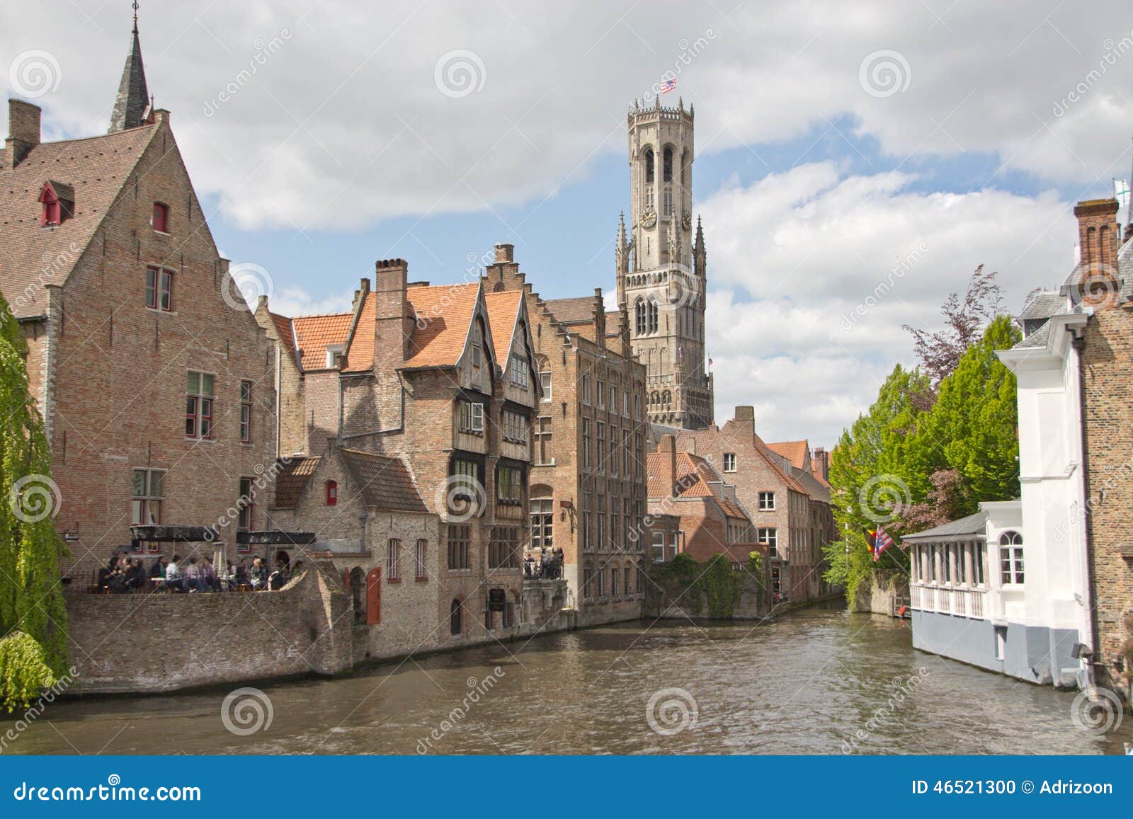 a canal in bruges, belgium, with the famous belfry in the background.