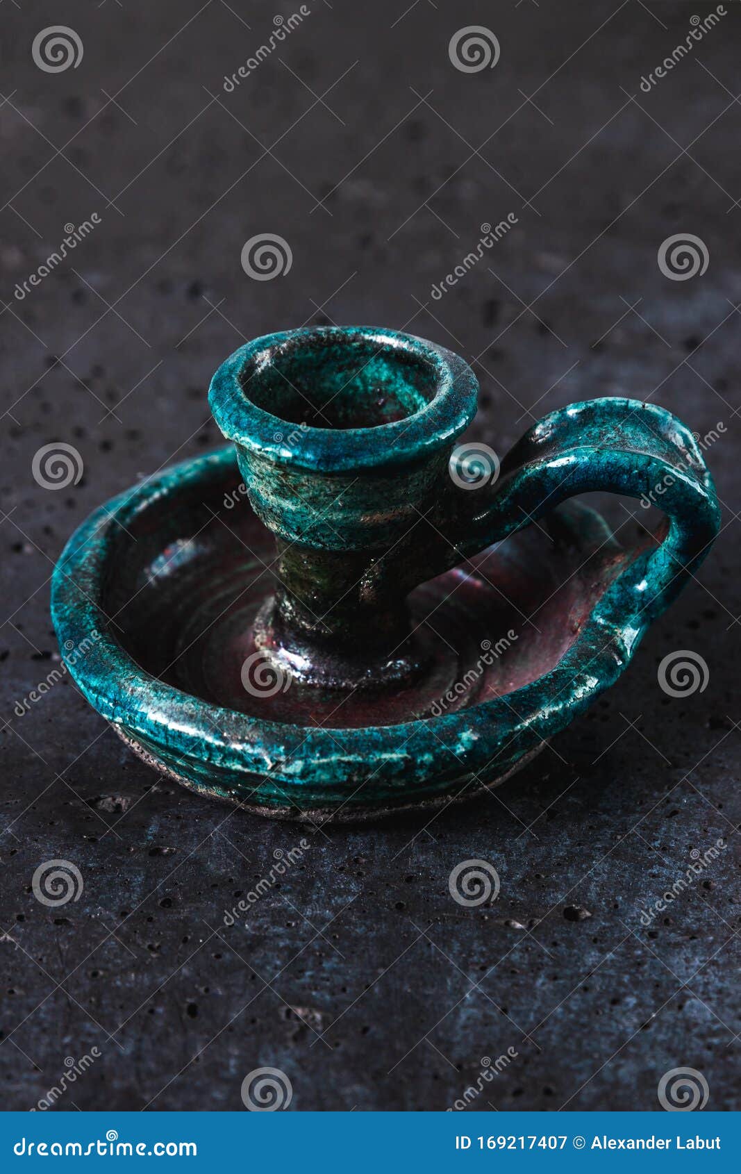 Candelabro de cerámica antigua de color turquesa sobre fondo de cemento gris, objeto antiguo diseñado para velas que representan una exquisita decoración casera, foto vertical