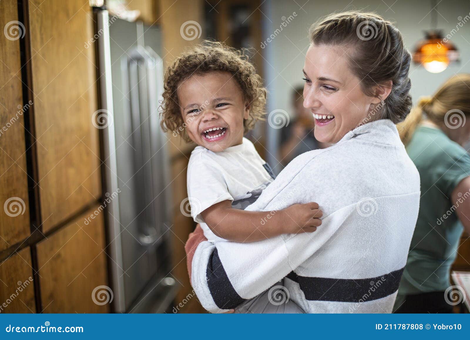 candid indoor photo of a smiling, cute mixed race child and his mother