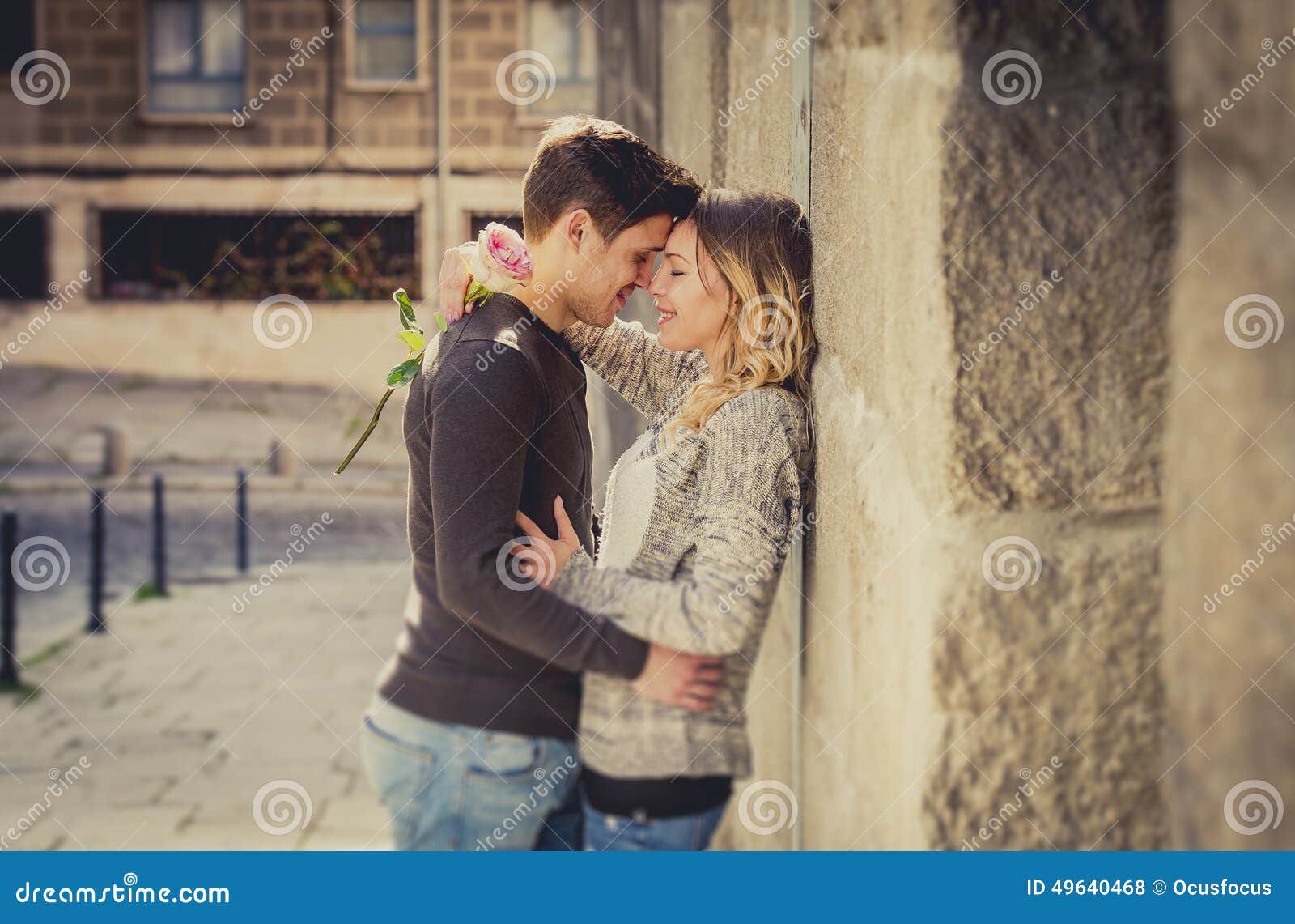 candid portrait of beautiful european couple with rose in love kissing on street alley celebrating valentines day