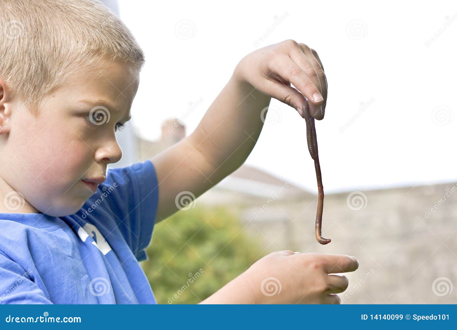 candid portrait of boy playing with a worm