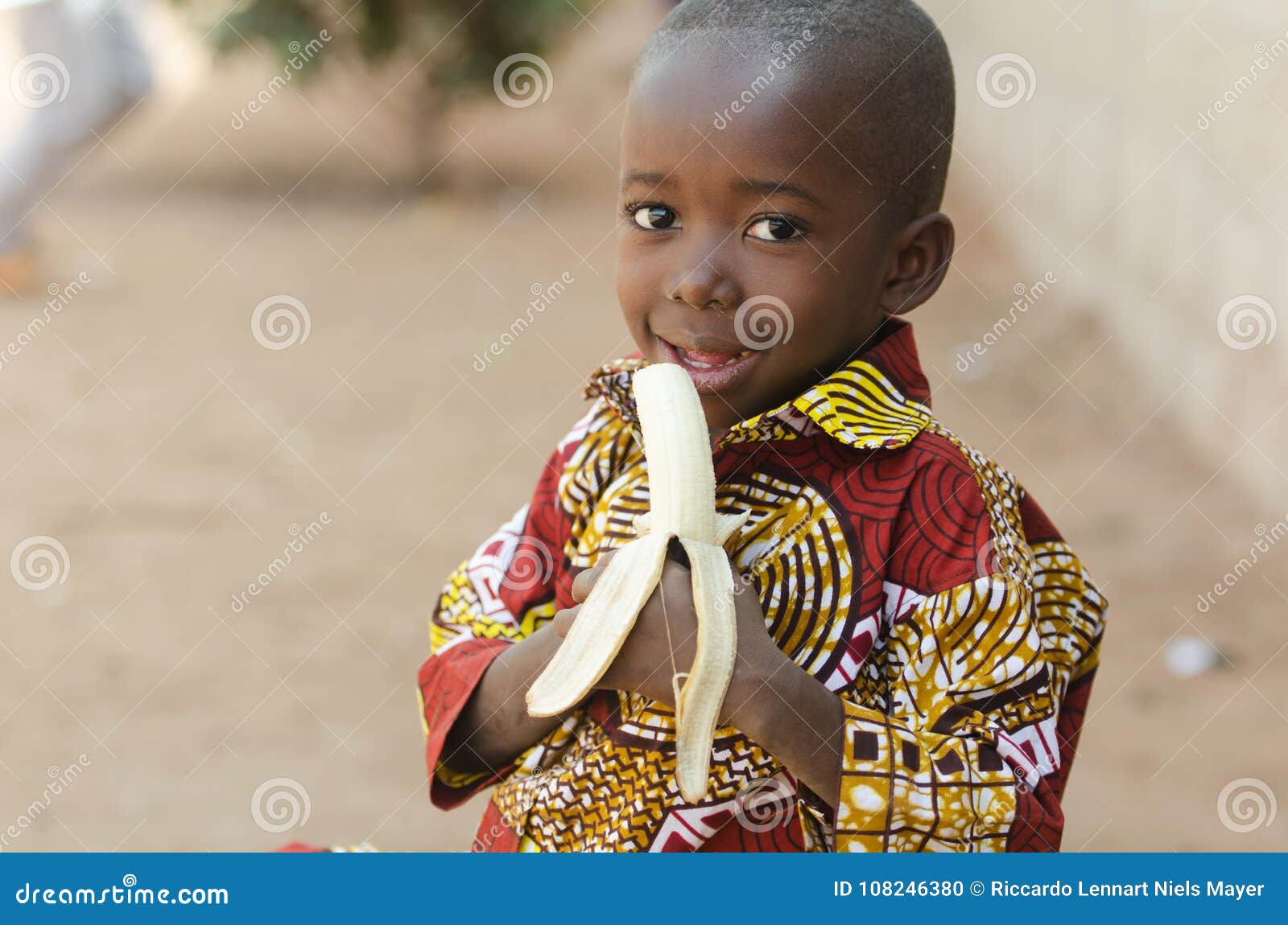 candid shot of african black boy eating banana outdoor