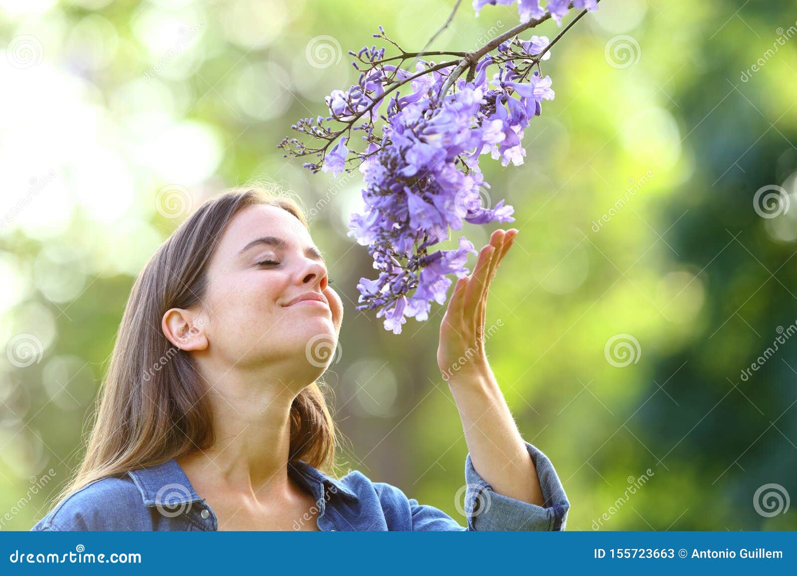 candid woman smelling flowers in a park