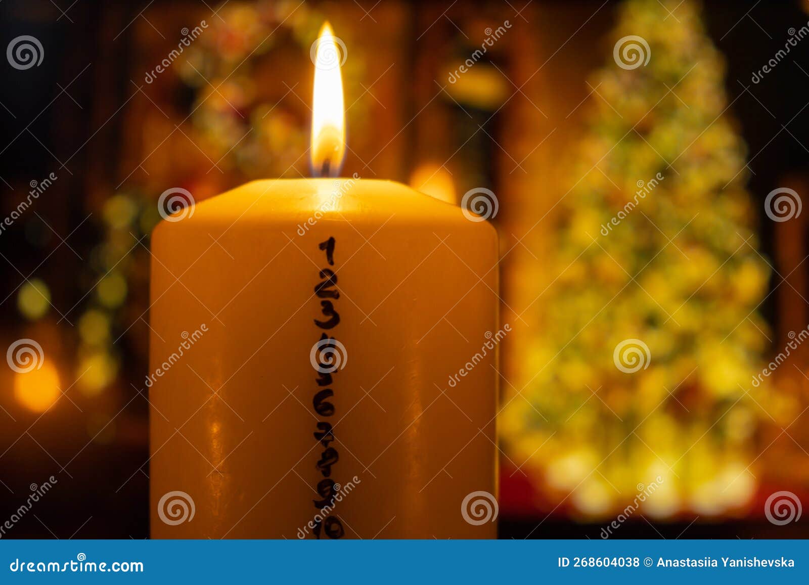candle with advent calendar on background of christmas tree lights decorations. traditional burning christmas wax