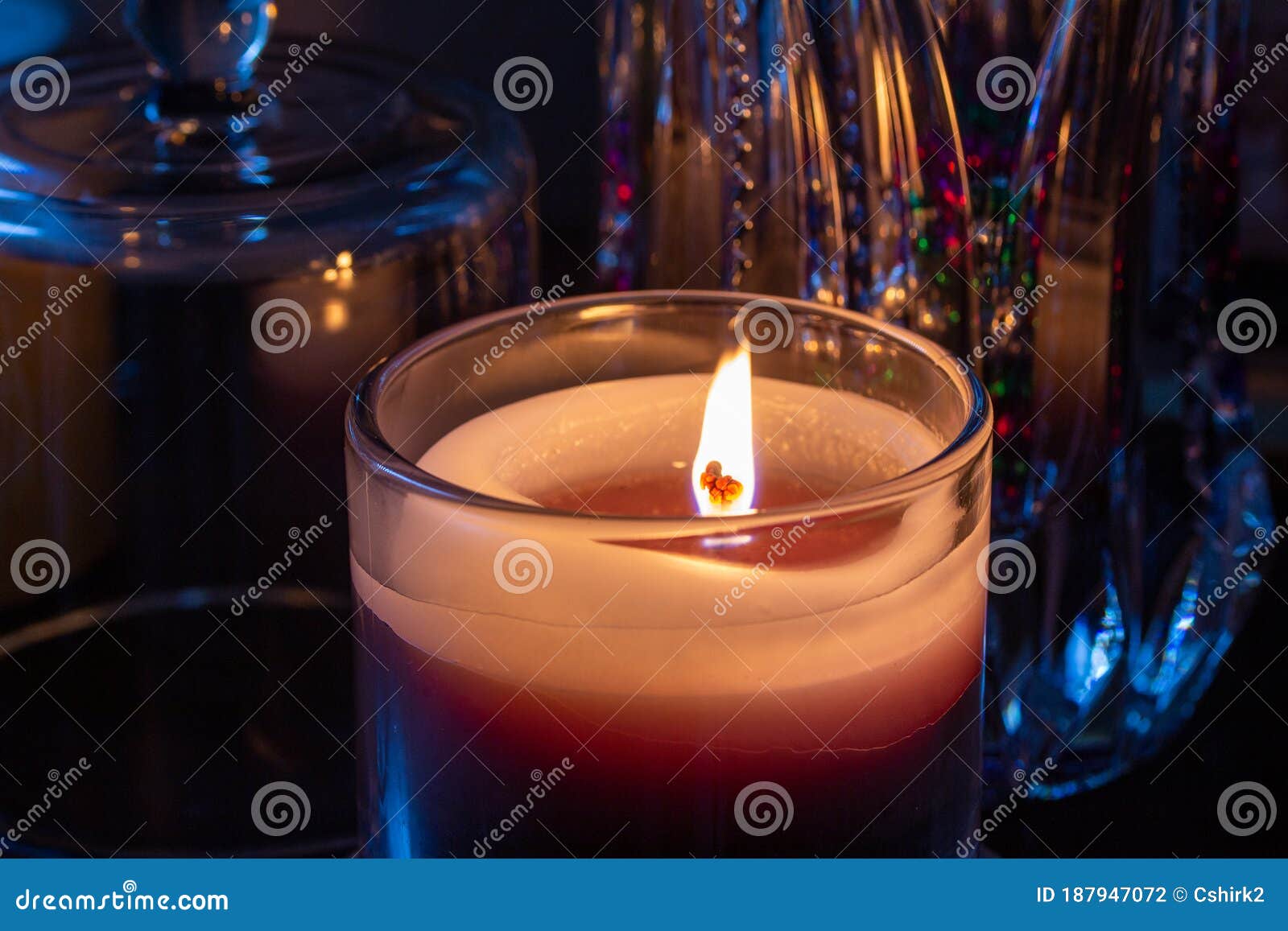 Candle in Glass Texture Illuminating Nearby Objects in Low Light Stock