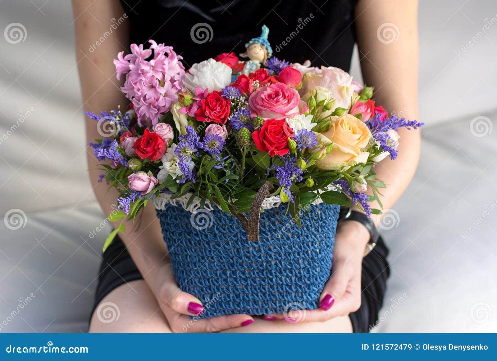 Canestro con i fiori luminosi alla mano della ragazza