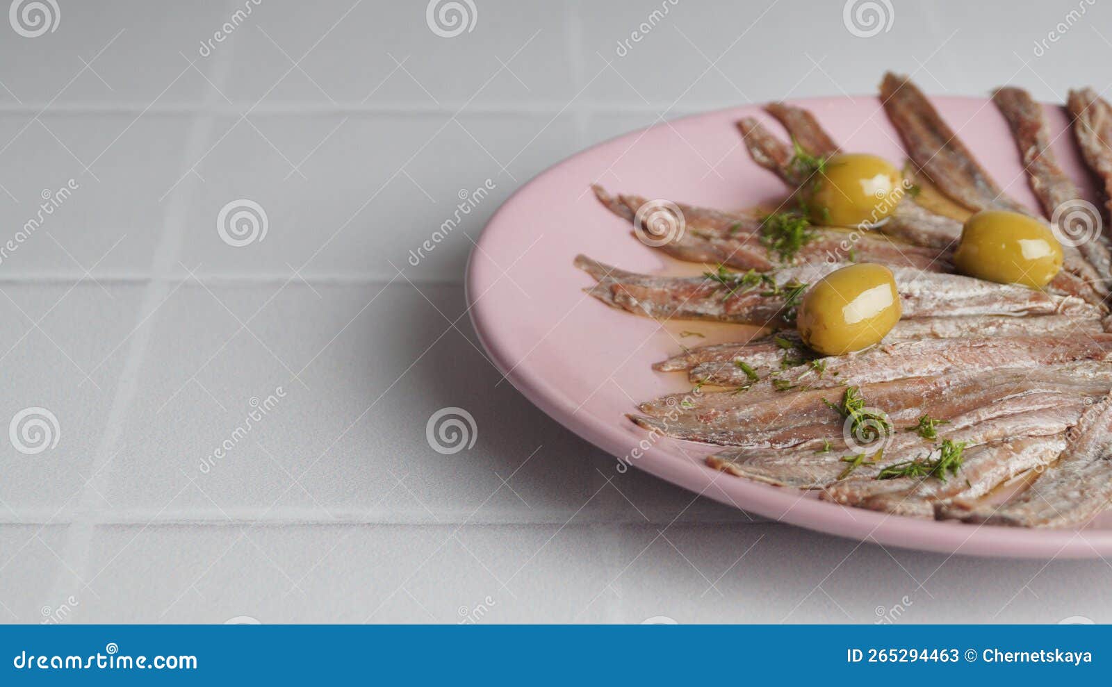 Canned Anchovy Fillets with Olives on White Tiled Table, Space for Text