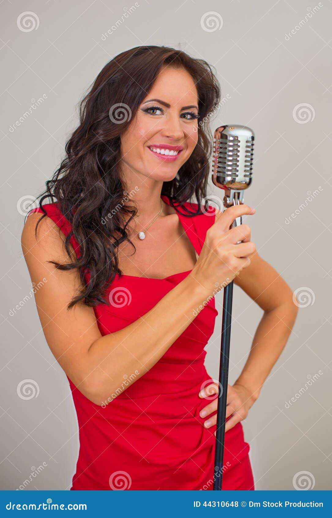 Canto castana attraente della donna nel microfono d'annata