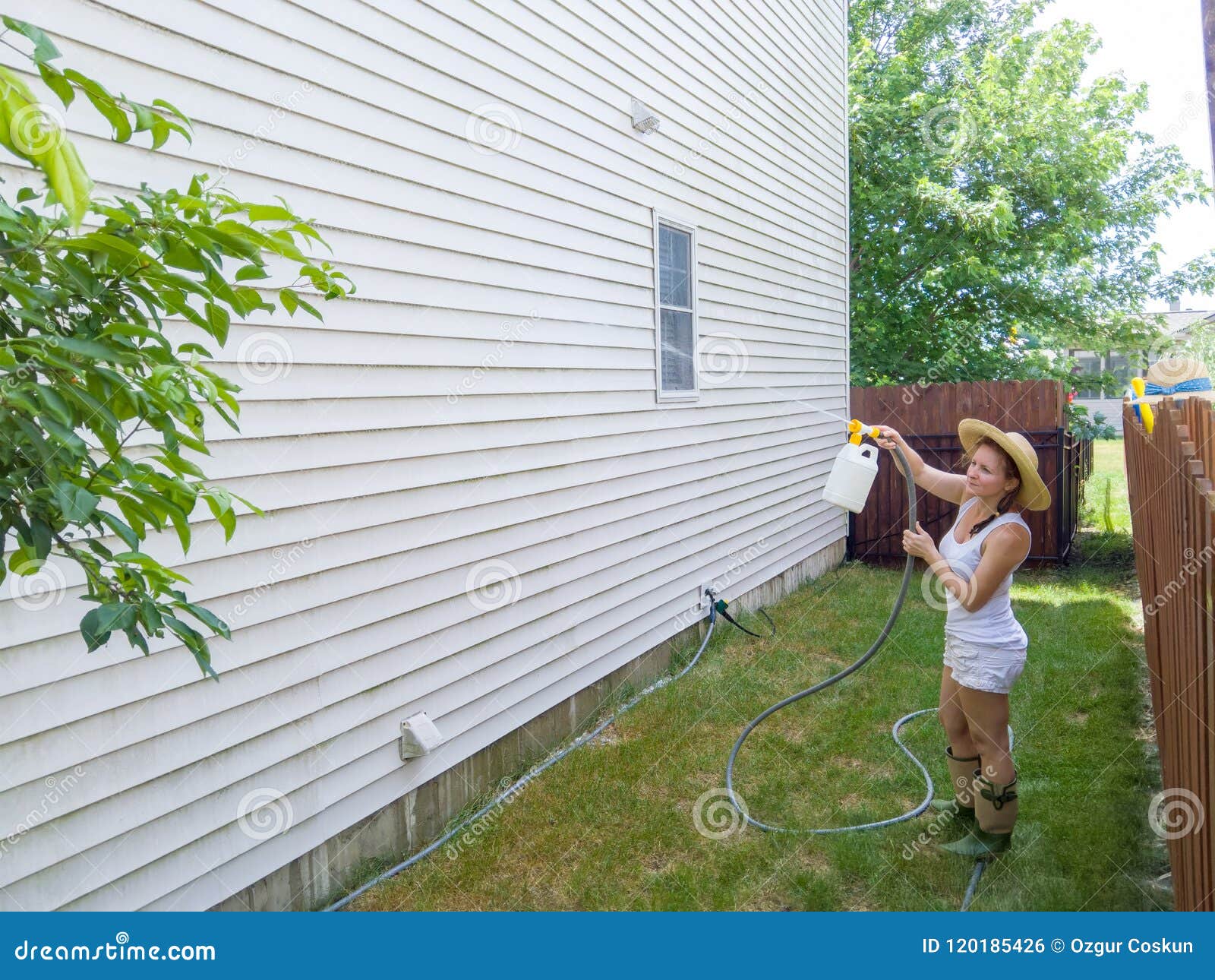 capable fit woman spraying down house sidings